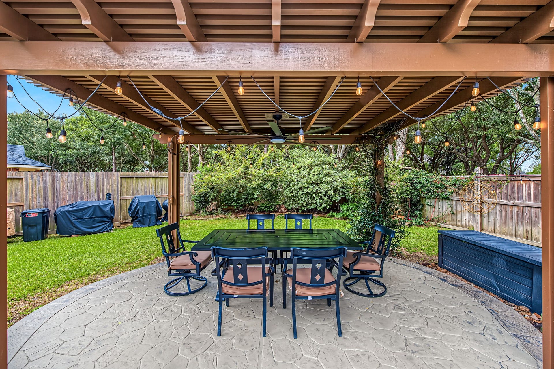 21223 Dover Park Lane, Katy, TX 77450 Charming backyard pergola with string lights offers a perfect outdoor dining area, surrounded by lush greenery and a cozy seating arrangement.