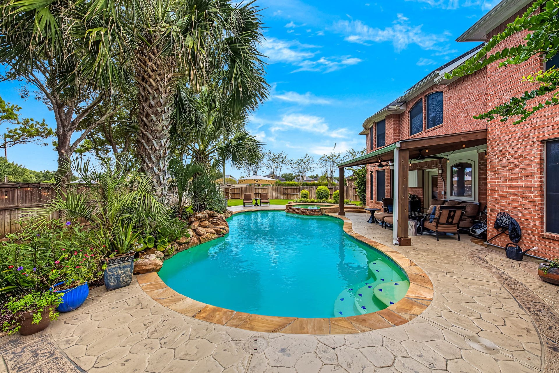 21223 Dover Park Lane, Katy, TX 77450 Tropical oasis featuring a sparkling pool surrounded by lush landscaping and a spacious covered patio, perfect for outdoor relaxation and entertaining.