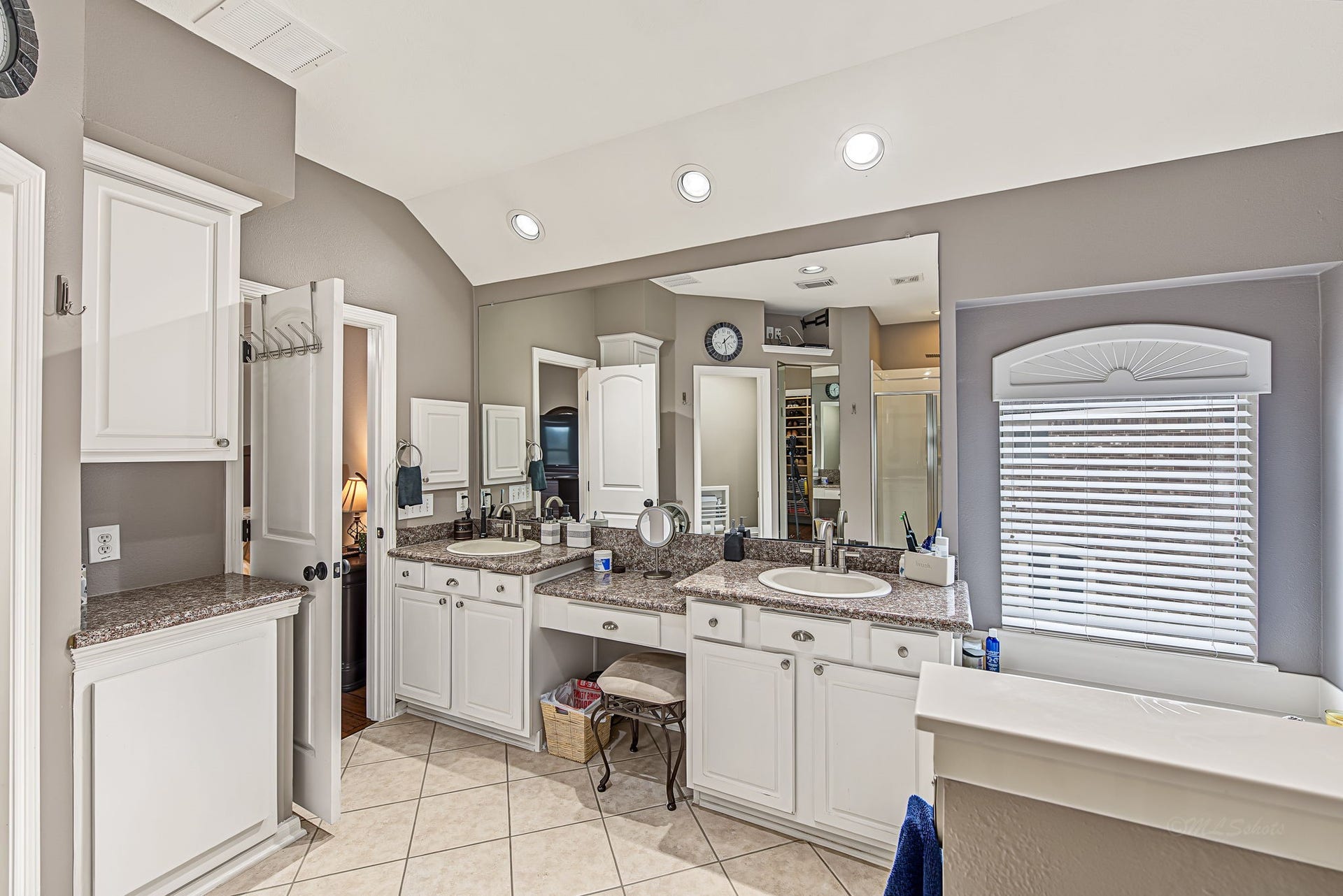 21223 Dover Park Lane, Katy, TX 77450 Spacious bathroom featuring dual sinks with granite countertops, ample cabinet storage, and a large mirror. Natural light streams through the window, enhancing the elegant tile flooring and modern fixtures.