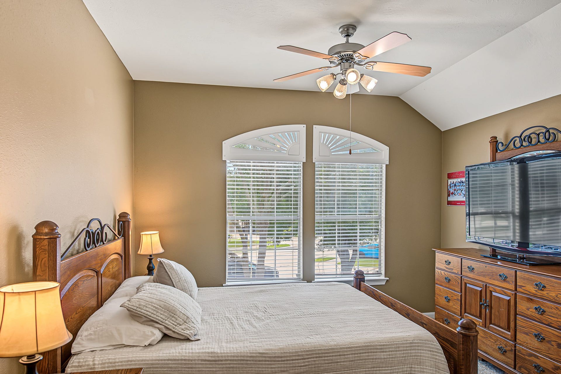 21223 Dover Park Lane, Katy, TX 77450 Cozy bedroom featuring a wooden bed frame, large arched windows allowing natural light, and a ceiling fan for comfort.