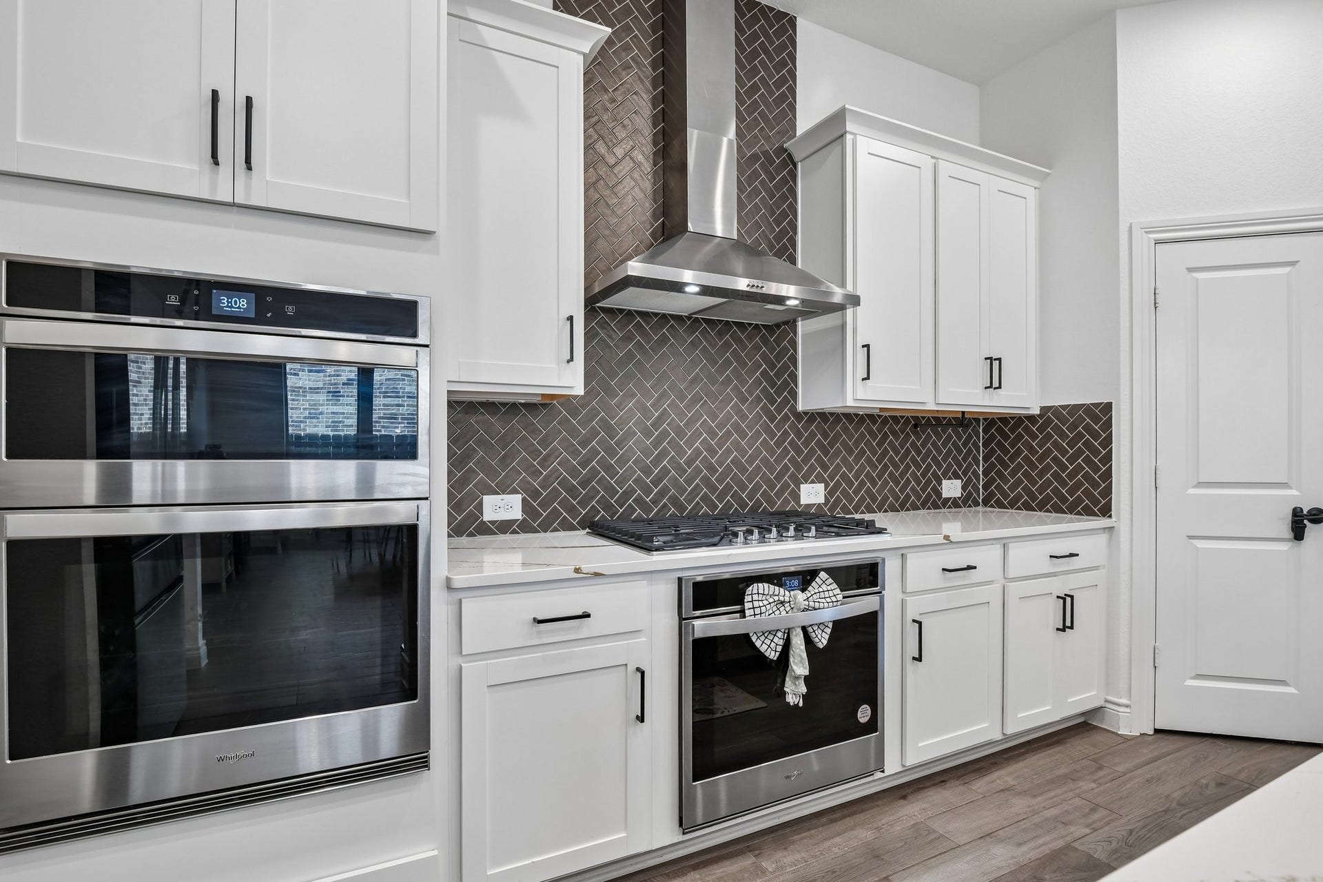 24110 Hawthorn Breeze Way, Katy, TX 77493 Built-in double ovens, gas cooktop, stainless vent hood, and herringbone tile backsplash