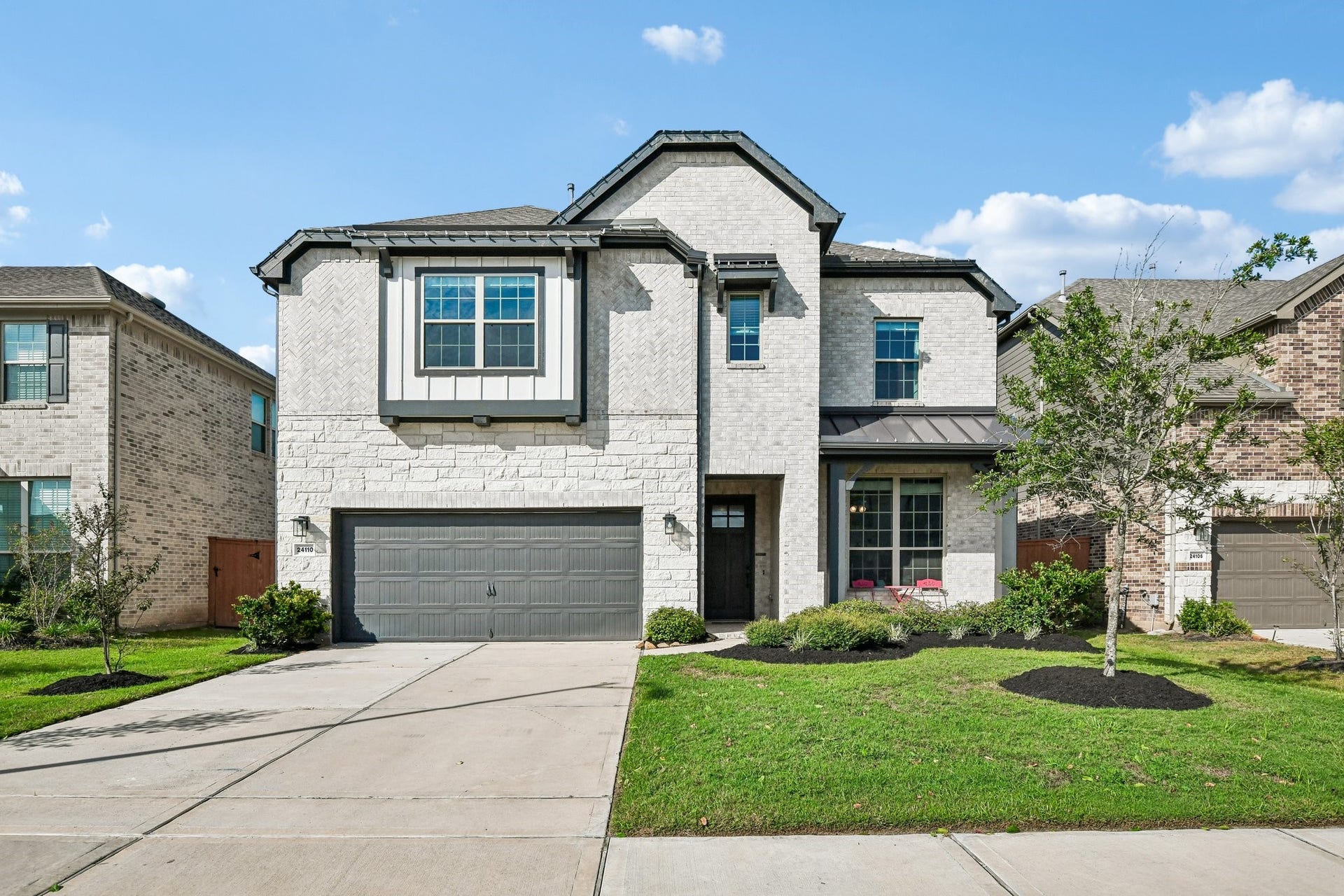 24110 Hawthorn Breeze Way, Katy, TX 77493 Wide front view showing the two-car garage, driveway, covered entry, and landscaped yard
