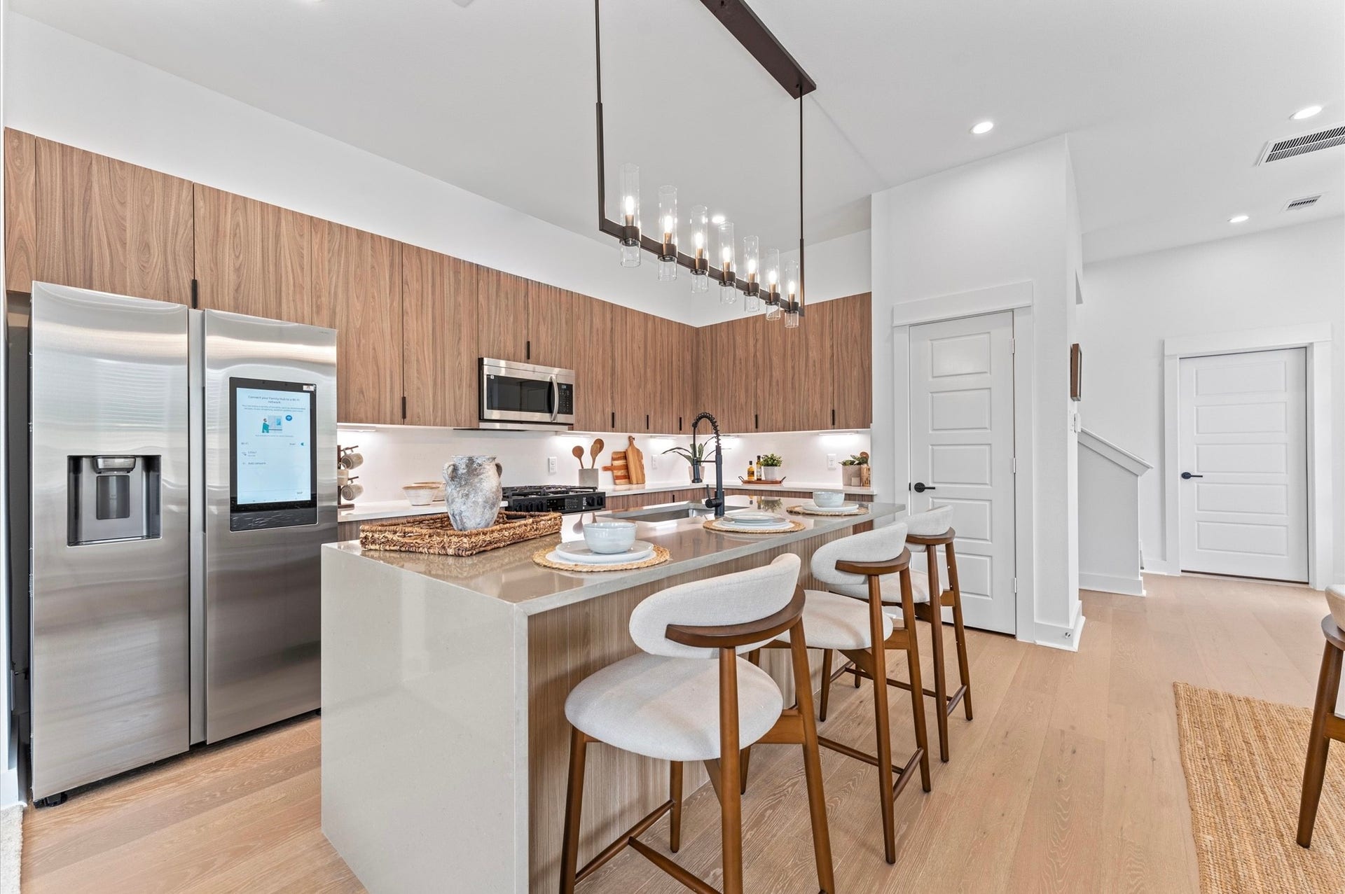 1009 Tuskegee Heights Lane, Houston, TX 77091 This stunning kitchen island is the centerpiece of a modern open-concept layout, featuring a waterfall quartz countertop that cascades elegantly down one side for high-end look. Positioned to offer clear sightlines to the living and dining areas, as well as through French doors to the balcony, the island enhances both functionality and flow. Contemporary finishessuch as sleek cabinetry, bold pendant lighting, and integrated appliancesadd sophistication, while bar seating invites casual dining.