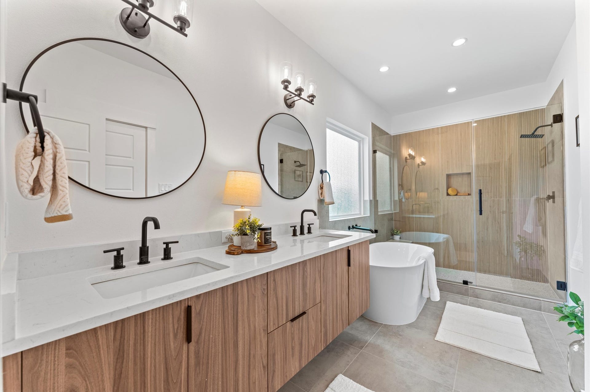 1009 Tuskegee Heights Lane, Houston, TX 77091 This luxurious primary bathroom blends modern elegance with spa-like comfort, featuring a spacious layout and contemporary selections throughout. A sleek double vanity with minimalist cabinetry and quartz countertops offers ample storage and style, while the glass-enclosed shower includes a built-in bench for added relaxation and convenience. The centerpiece is a sculptural freestanding soaking tub, perfectly positioned to invite unwinding after a long day.