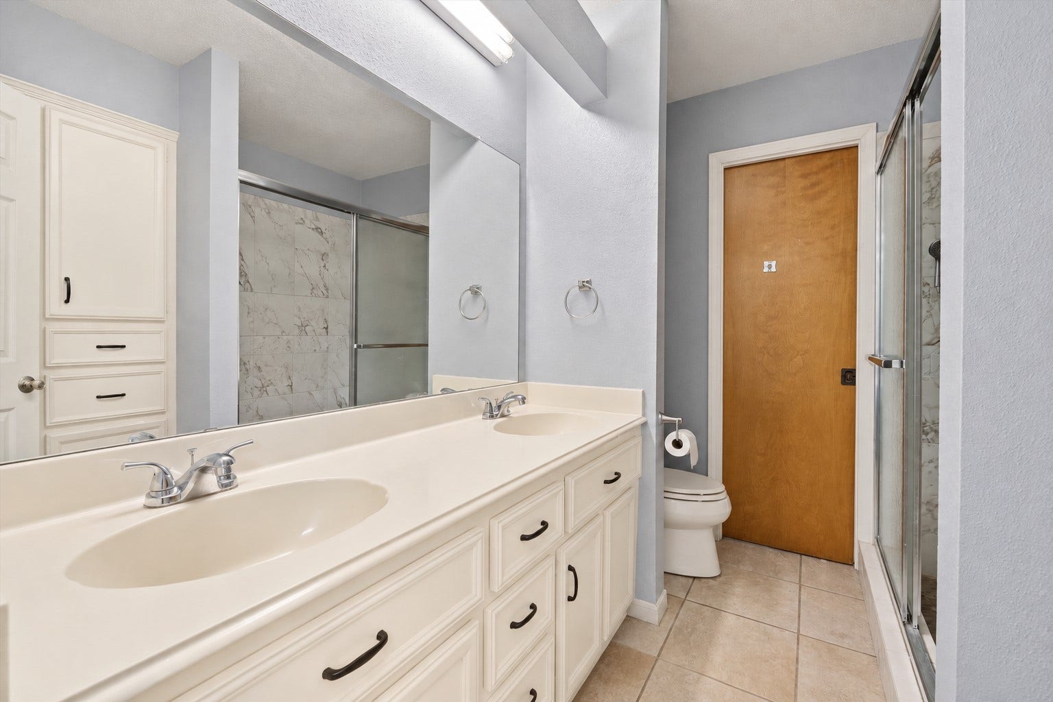 2309 Halbert Drive, Pearland, TX 77581 The bathroom features a double sink vanity, a toilet, and a spacious walk-in shower, offering a clean, functional design with everyday comfort in mind.