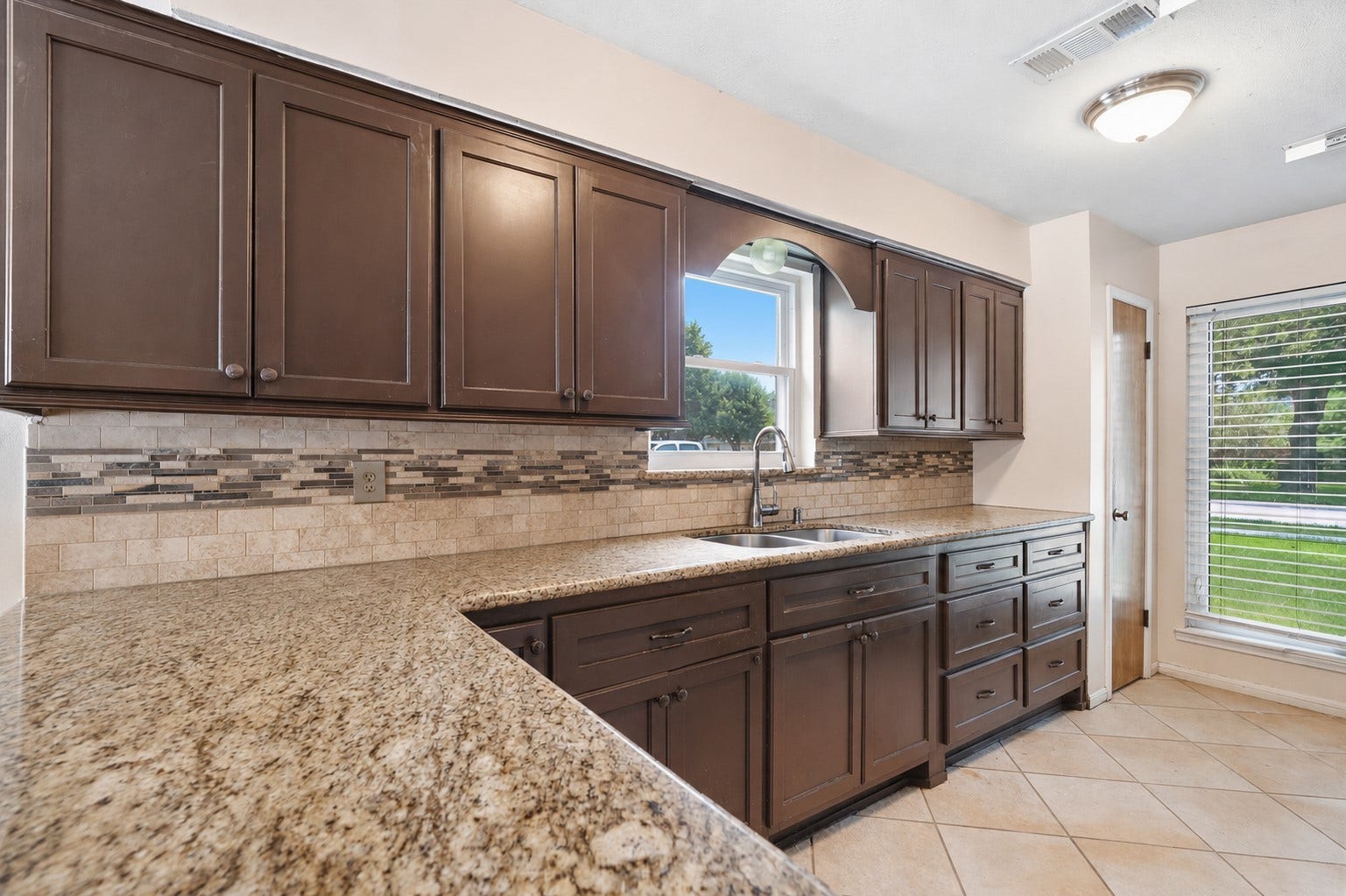 2309 Halbert Drive, Pearland, TX 77581 This stunning kitchen showcases a peninsula kitchen island, natural wood cabinetry, and classic dome lighting, blending contemporary elegance with warm, inviting style perfect for cooking and entertaining in style.