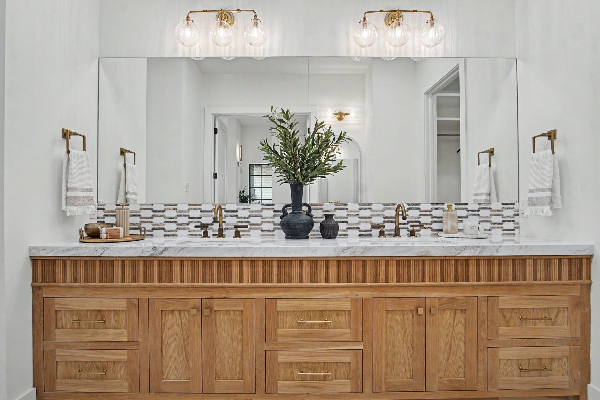 705 Walton Street, Houston, TX 77009 Elegant bathroom features a spacious double vanity with rich wood cabinetry, marble countertop, and a stylish mosaic tile backsplash.