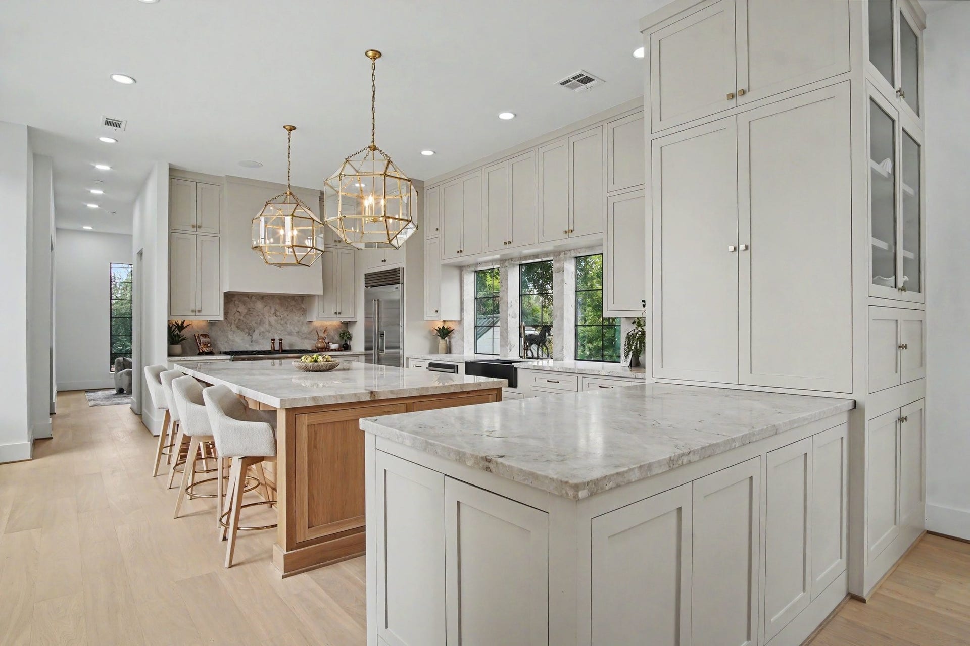 705 Walton Street, Houston, TX 77009 Elegant kitchen featuring a spacious island with Taj Mahal quartzite countertops, modern pendant lighting, and sleek custom built on-site cabinetry offering ample storage.