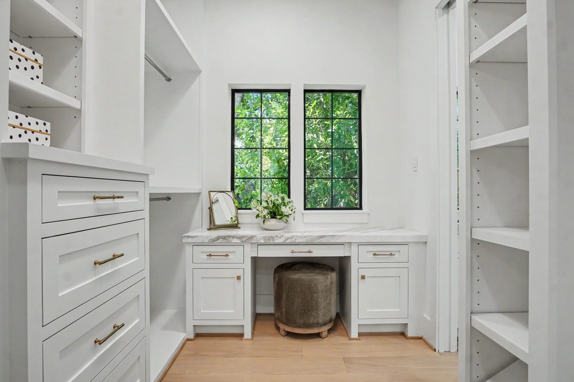 705 Walton Street, Houston, TX 77009 Elegant walk-in closet featuring custom cabinetry, a built-in vanity, and ample natural light from a charming window.