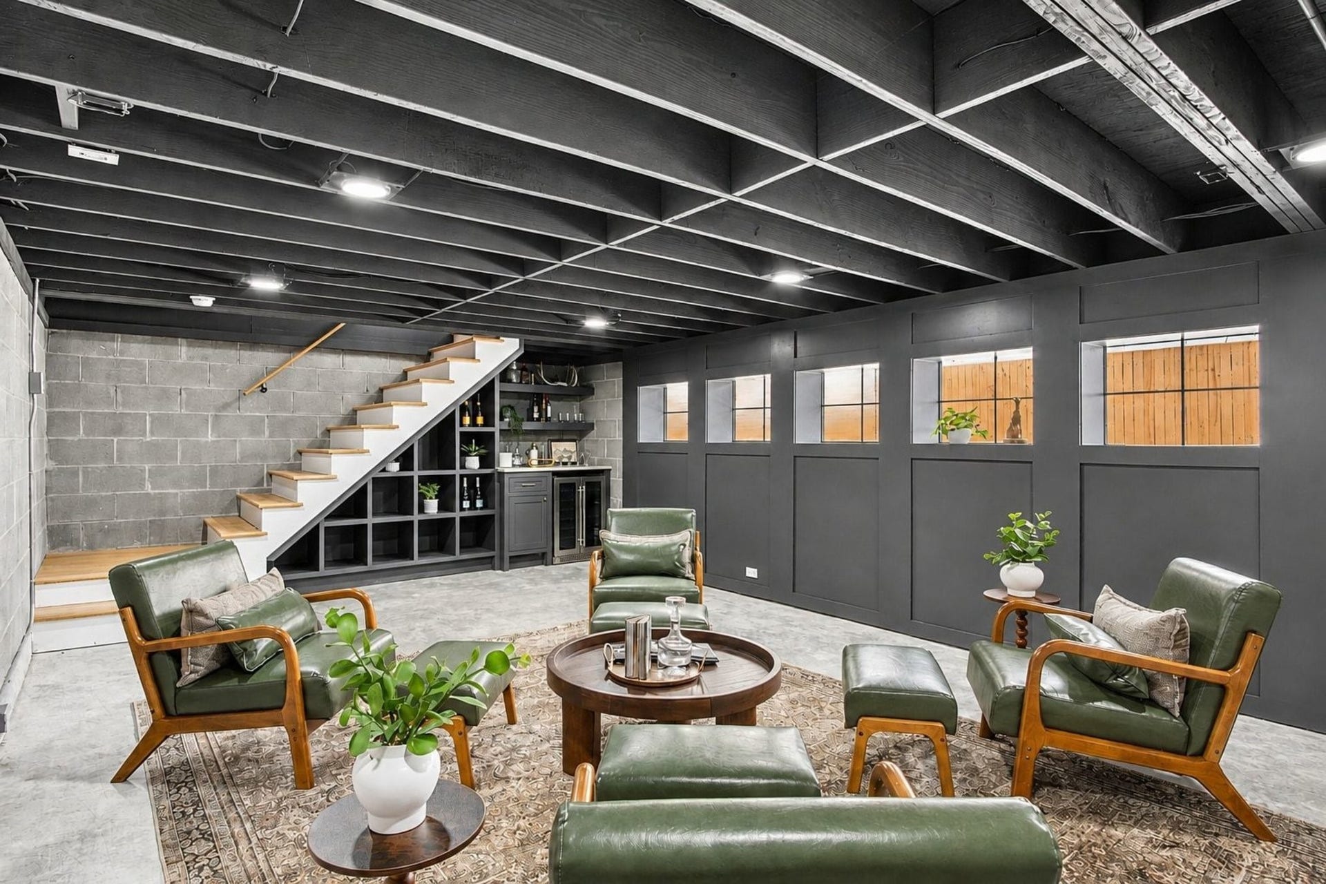 705 Walton Street, Houston, TX 77009 Stylish basement lounge with exposed beams features a cozy seating area and built-in shelving, perfect for entertaining.