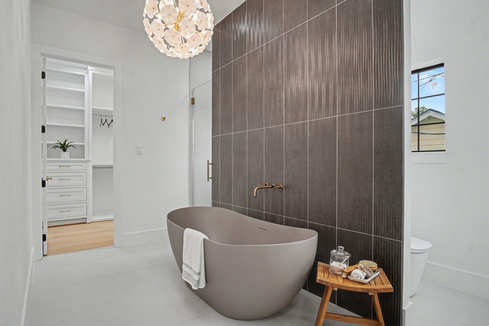 705 Walton Street, Houston, TX 77009 Luxurious bathroom featuring a modern freestanding tub against a sleek, dark accent wall, complemented by elegant fixtures and a stylish chandelier.