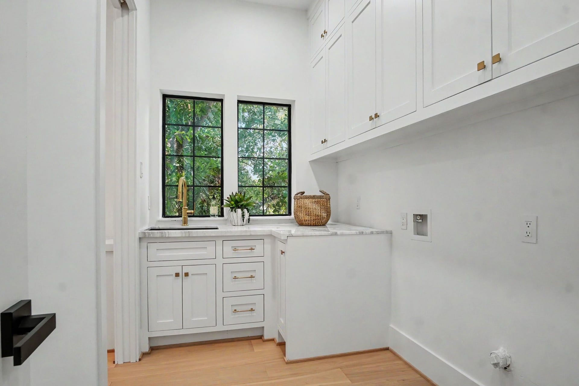705 Walton Street, Houston, TX 77009 Charming laundry room with elegant cabinetry for storage, a sink for handwashing delicates, marble countertops, and a large window offering natural light.