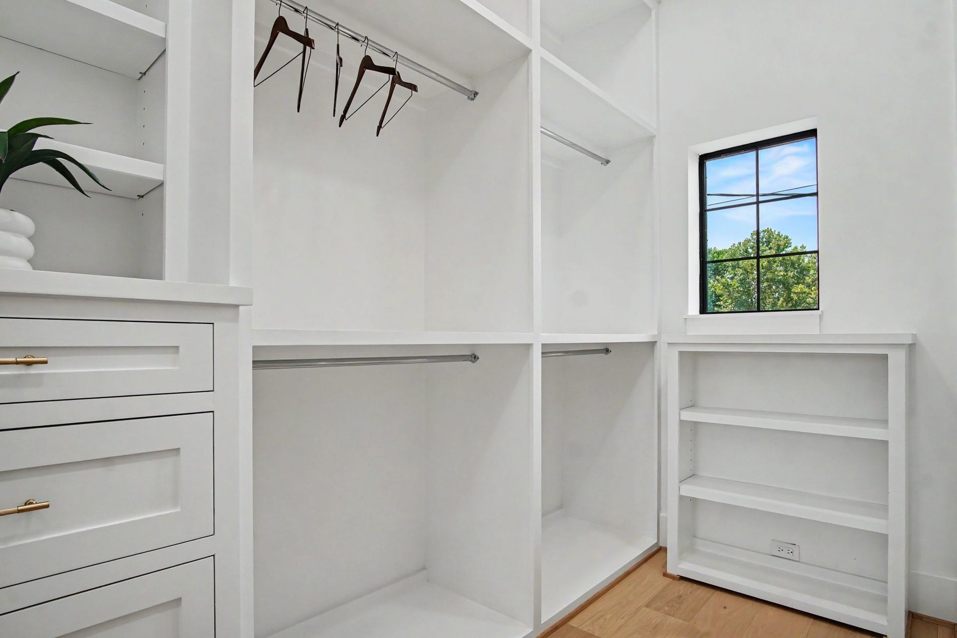 705 Walton Street, Houston, TX 77009 Secondary walk-in closet with ample shelving, hanging space, and natural light from a charming window, complemented by elegant cabinetry and sleek hardware.