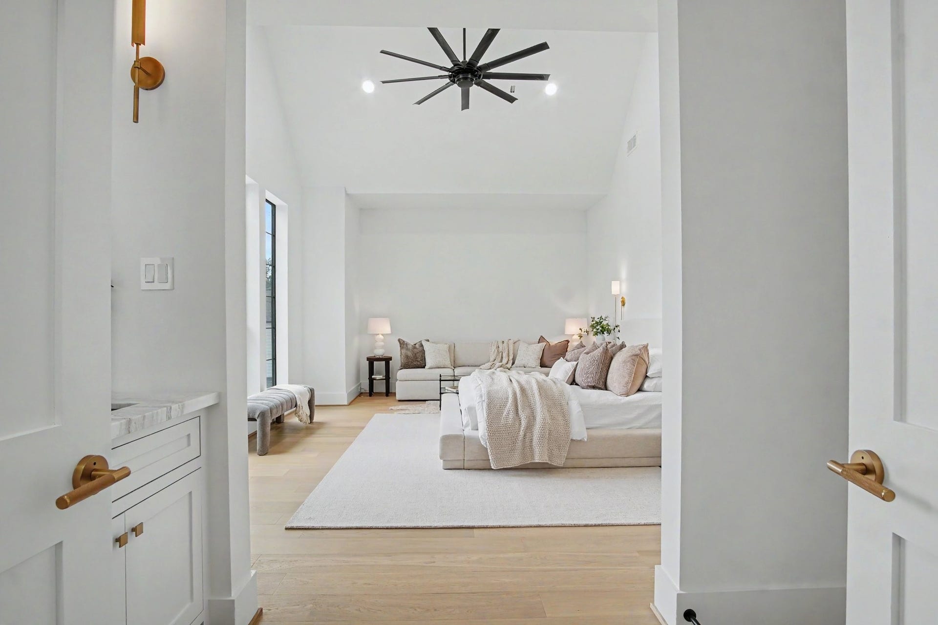 705 Walton Street, Houston, TX 77009 Elegant and spacious bedroom featuring high ceilings, a modern ceiling fan, and abundant natural light, complemented by a cozy seating area and neutral decor.