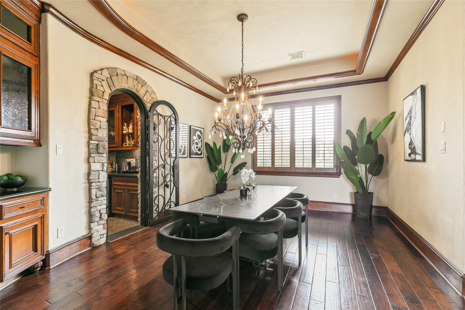 Grand dining room features gorgeous chandelier within tray ceiling and lovely stone accents and built-in cabinets.