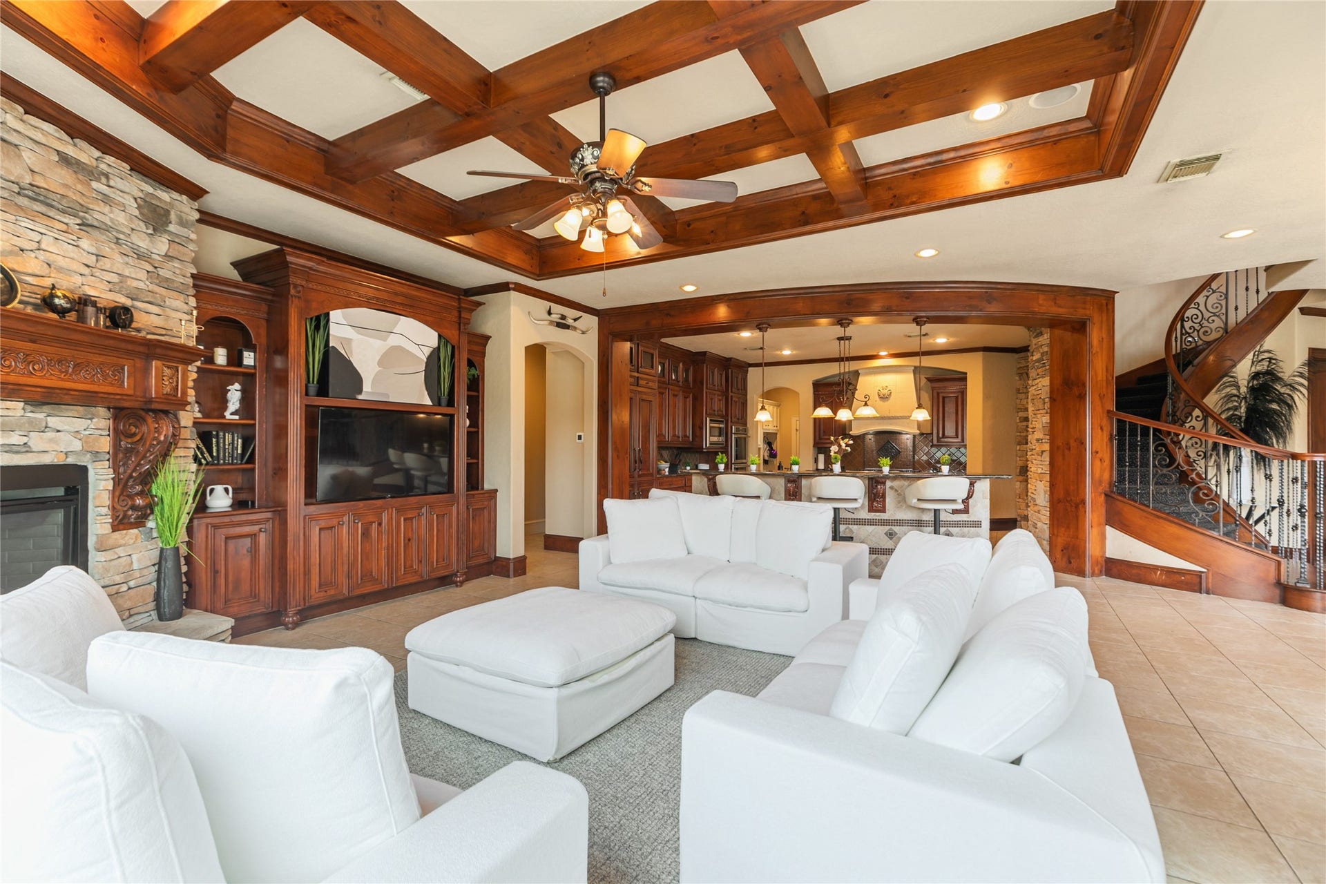 Inviting den highlighted by gorgeous accent beams and a stone fireplace with view of the kitchen.