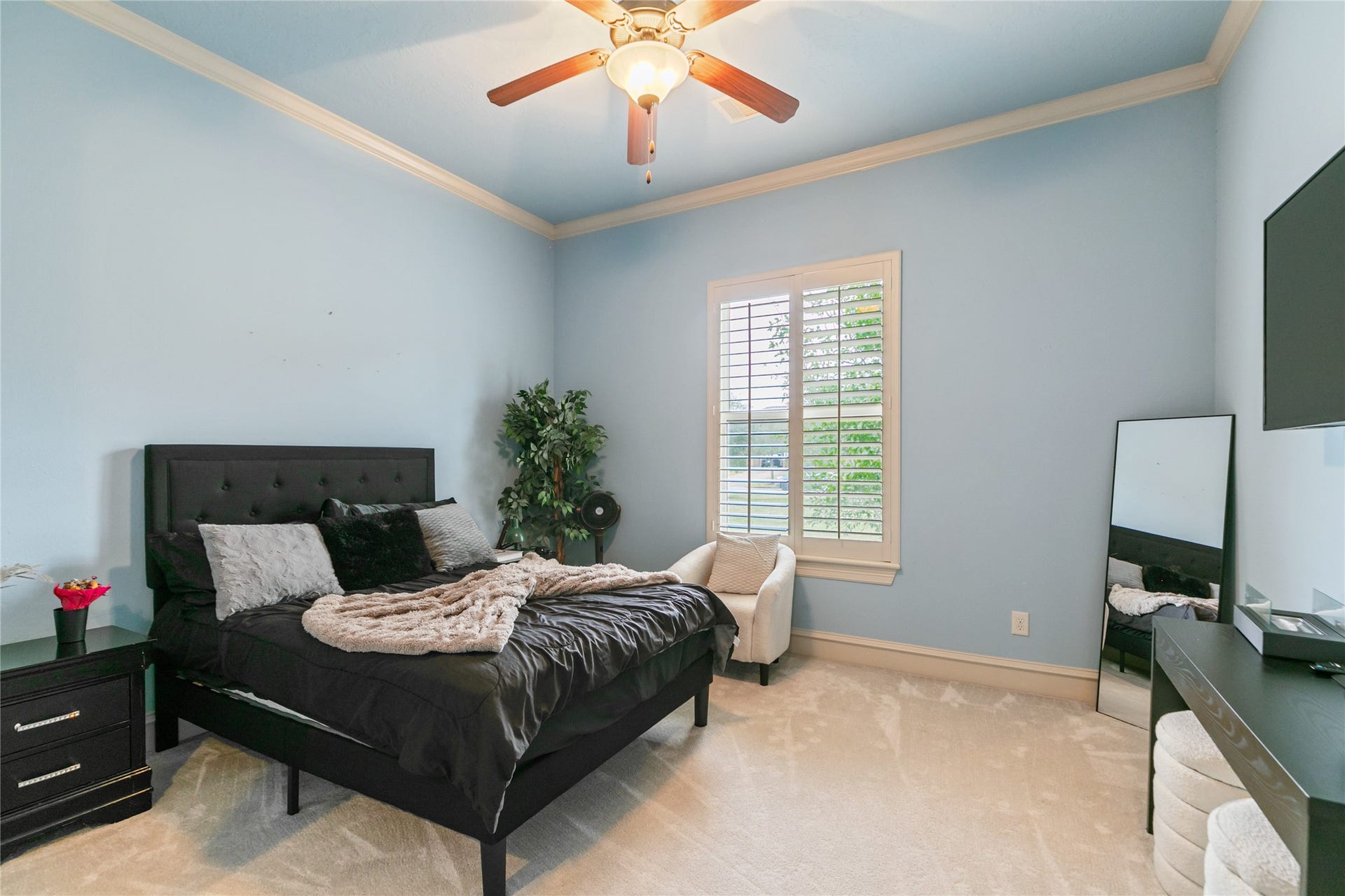 Bedroom (one of three) in attached apartment with large window with plantation shutters.
