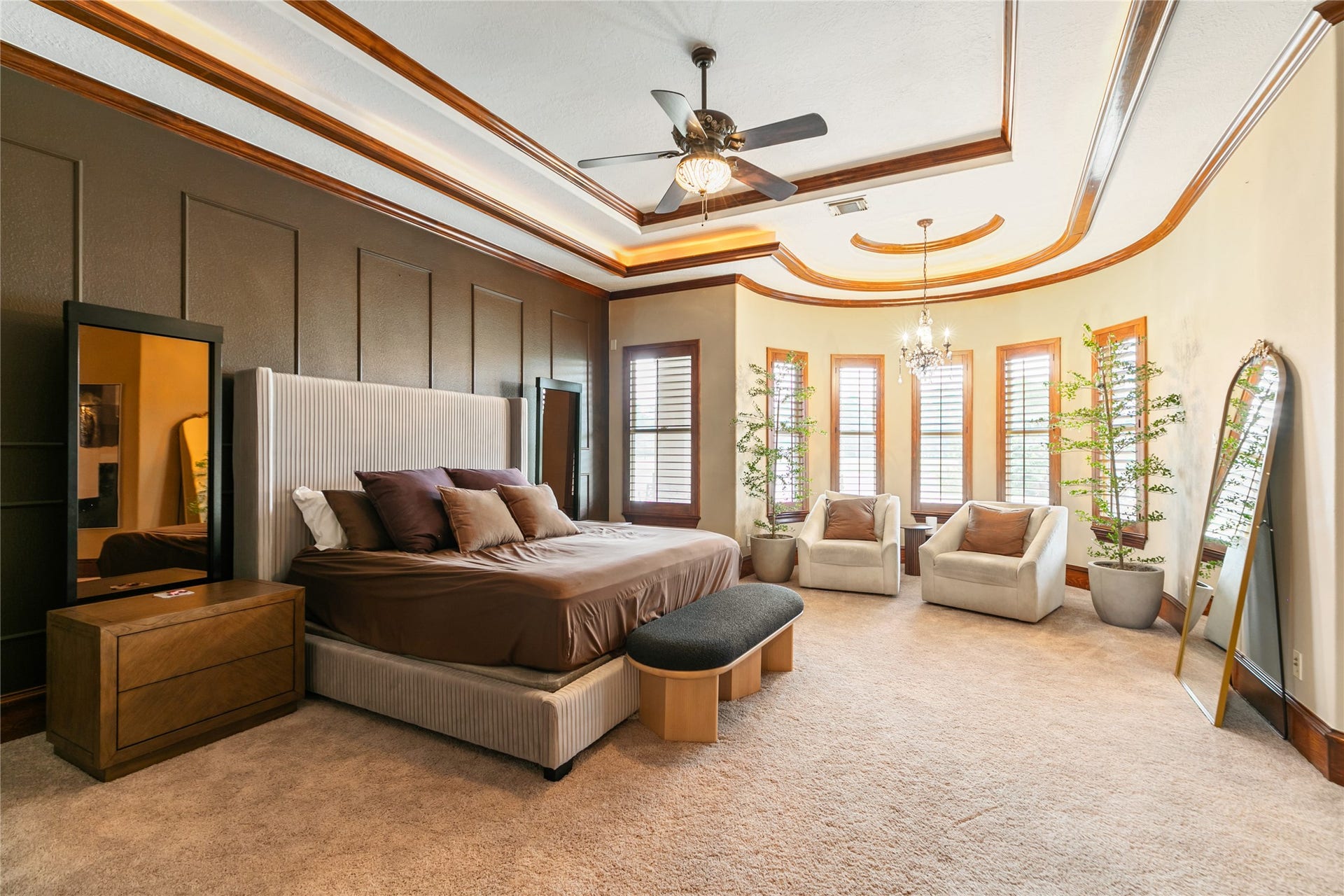 Bright and welcoming, the primary bedroom offers a comfortable seating area framed by a wall of windows.