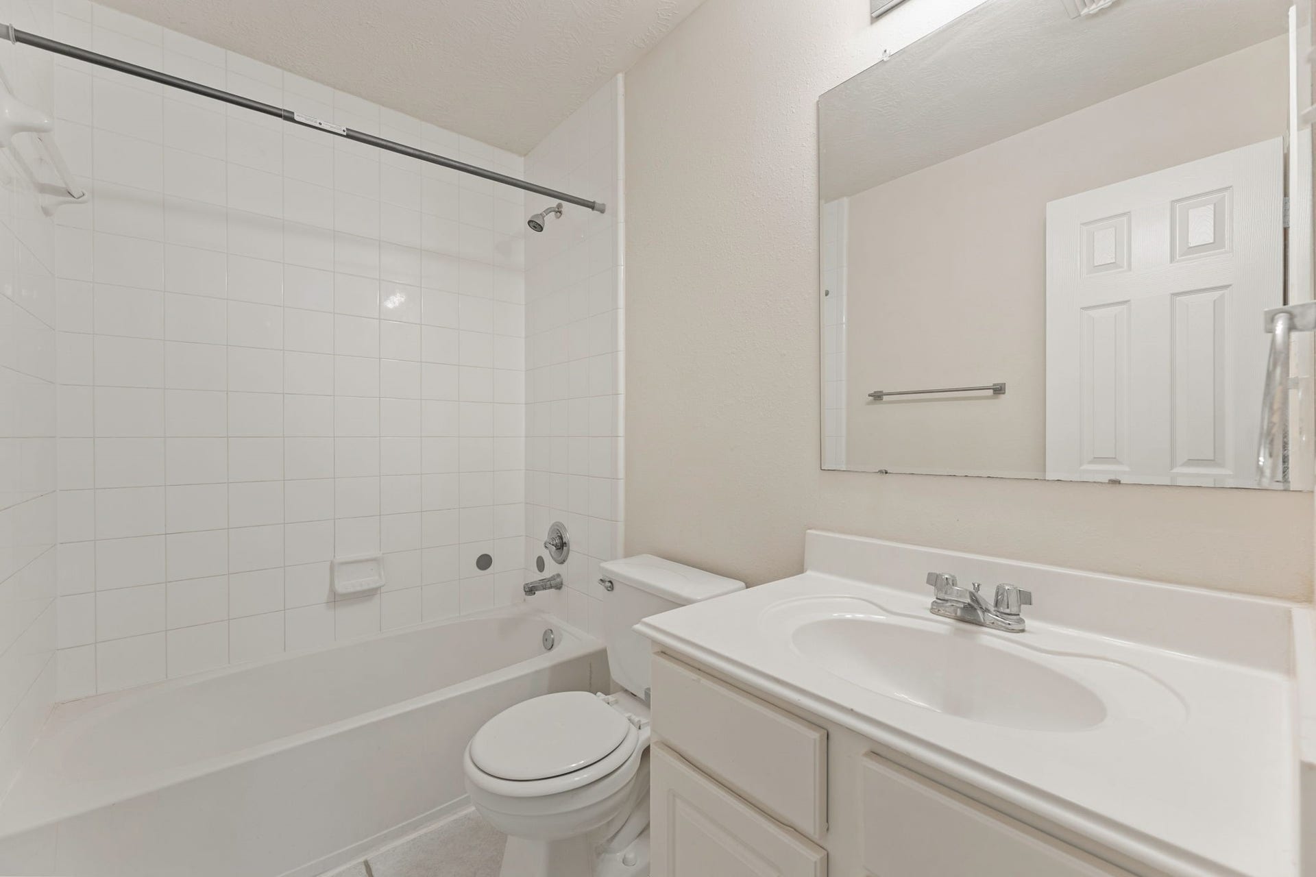 A full bath with a tub and shower combo in classic white tile and a single vanity.