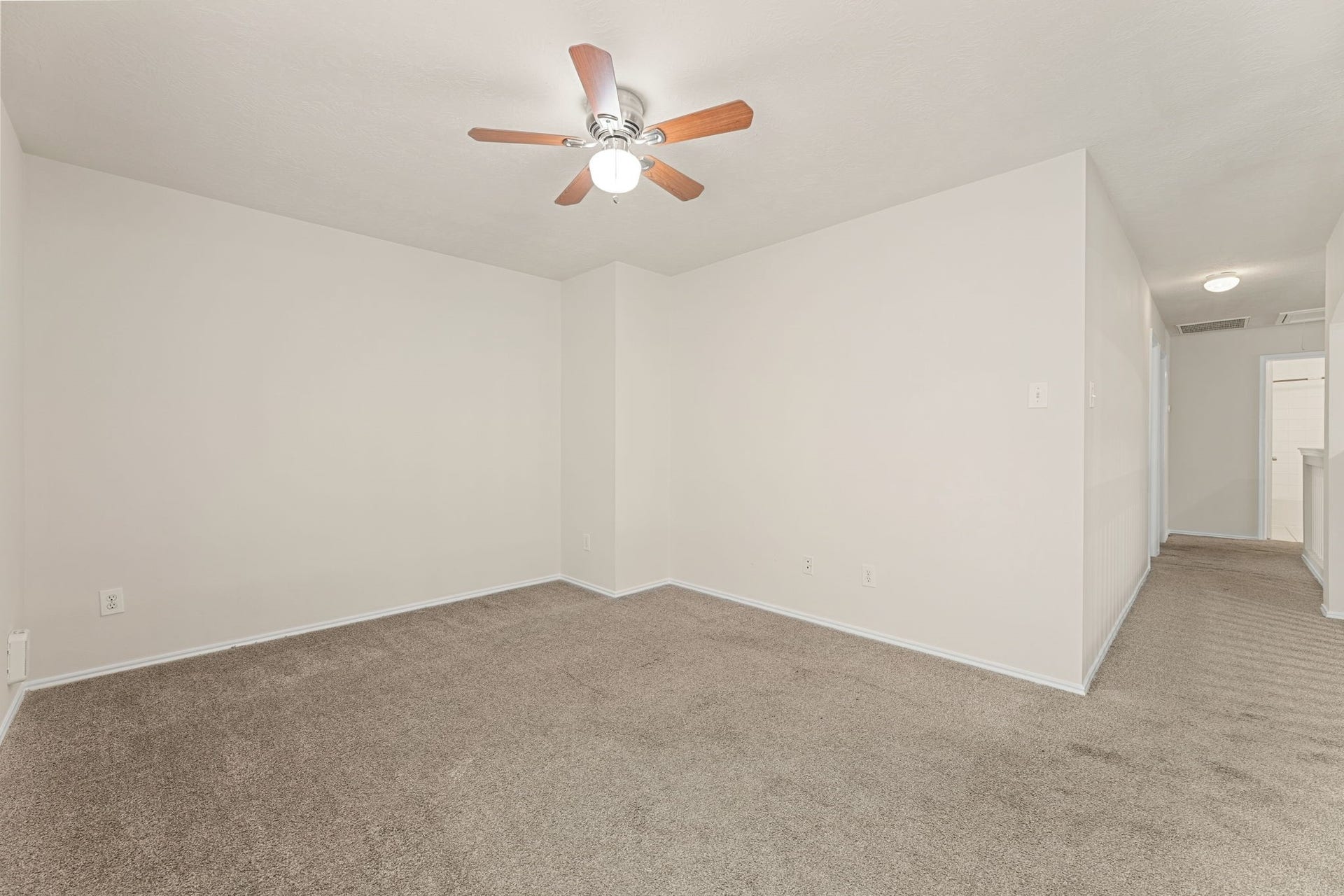 A large upstairs bonus room with a ceiling fan and a window, and plenty of space for a media room, playroom, or home gym.