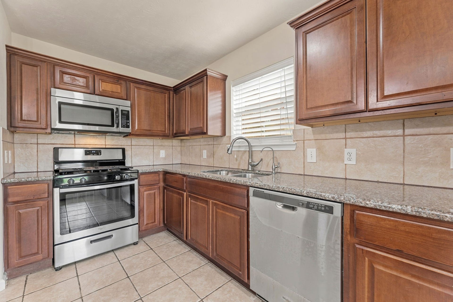 The stainless gas range sits under a built-in microwave, and the double sink has a pull-down faucet and a filtered water tap.