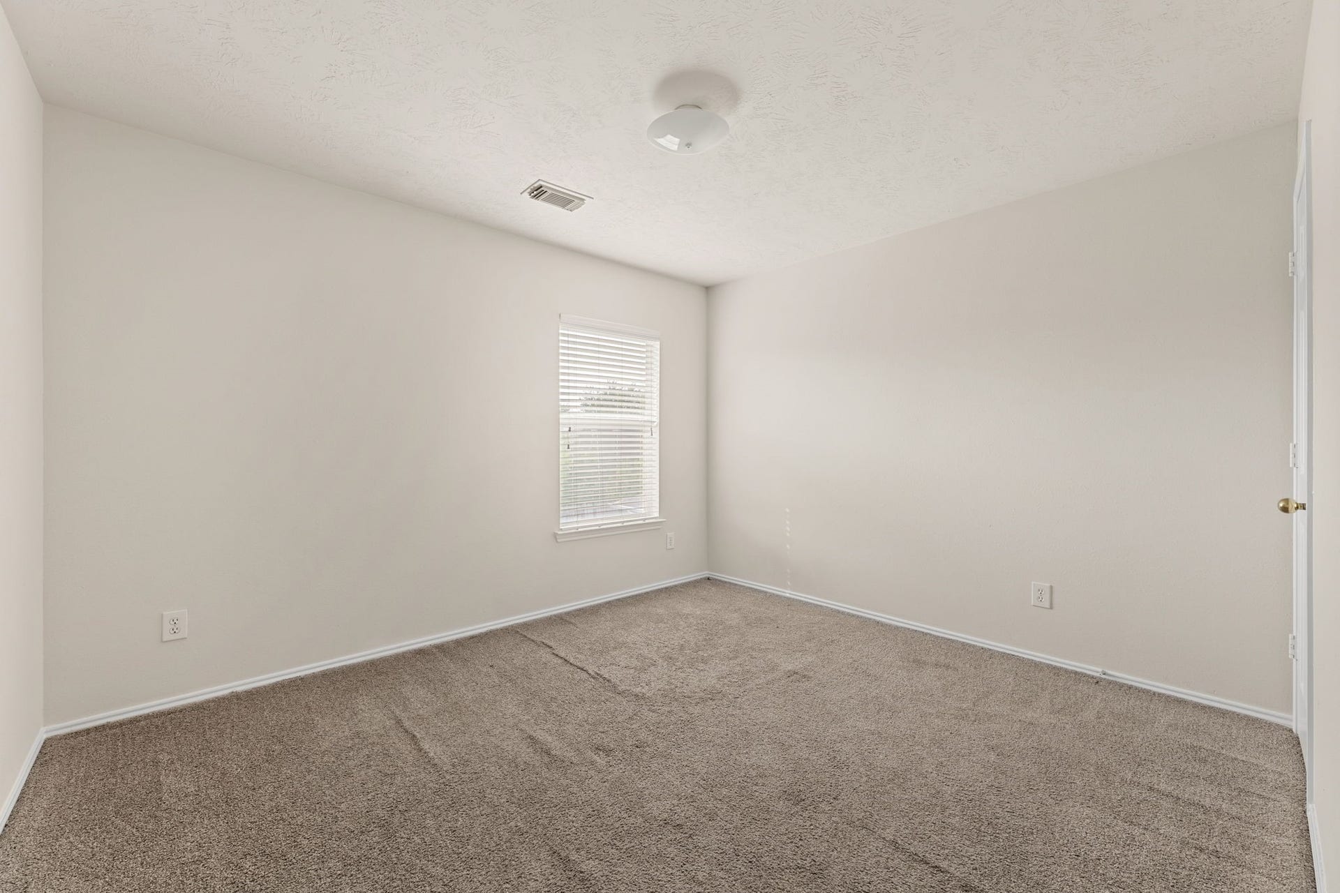 A bright secondary bedroom with a ceiling fan, a large window, and a double-door closet.