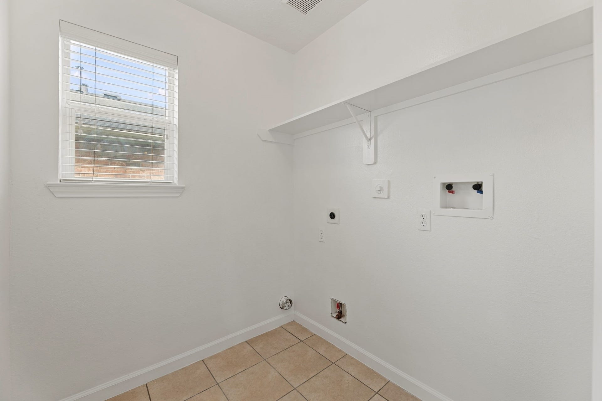 A dedicated utility room with a shelf and hookups for a washer and electric dryer.