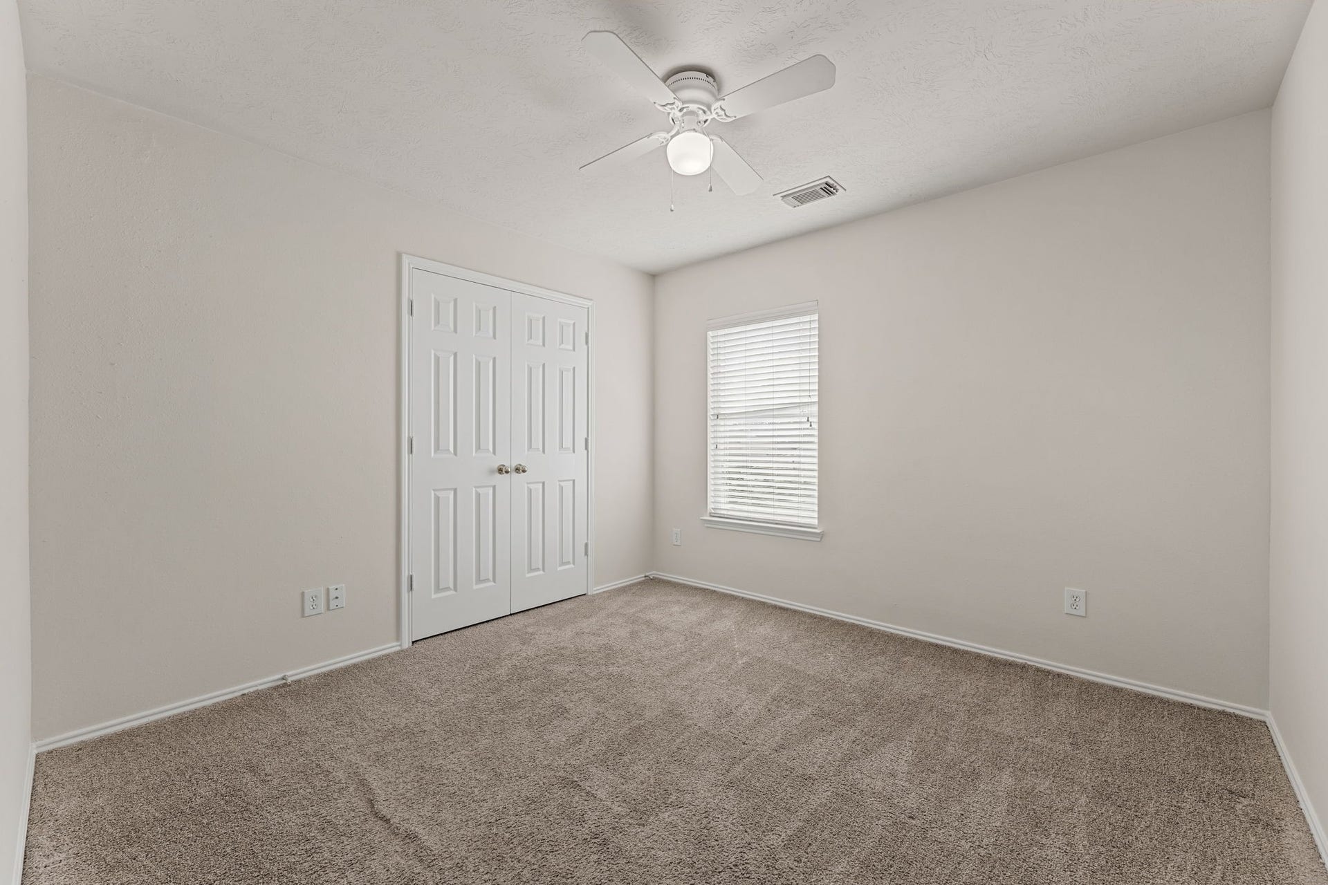 A cozy room with a big window, a closet, and a ceiling light, which works well as a bedroom, nursery, or office.