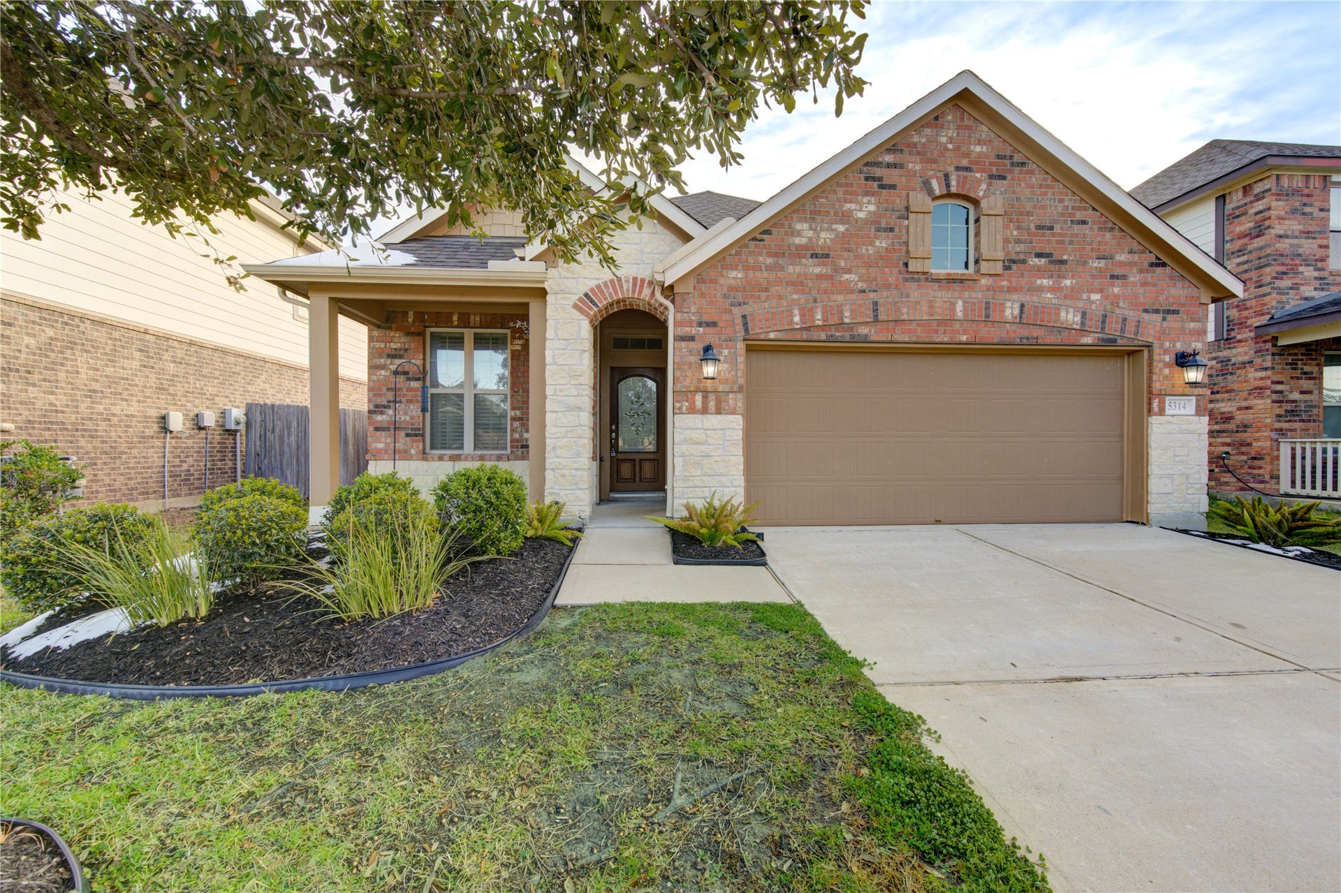 5314 Silver Ledge Drive, Katy, TX 77493 This modern kitchen features dark cabinetry, stainless steel appliances, and a large island with pendant lighting. The open layout and light tile flooring create a spacious and inviting atmosphere.
