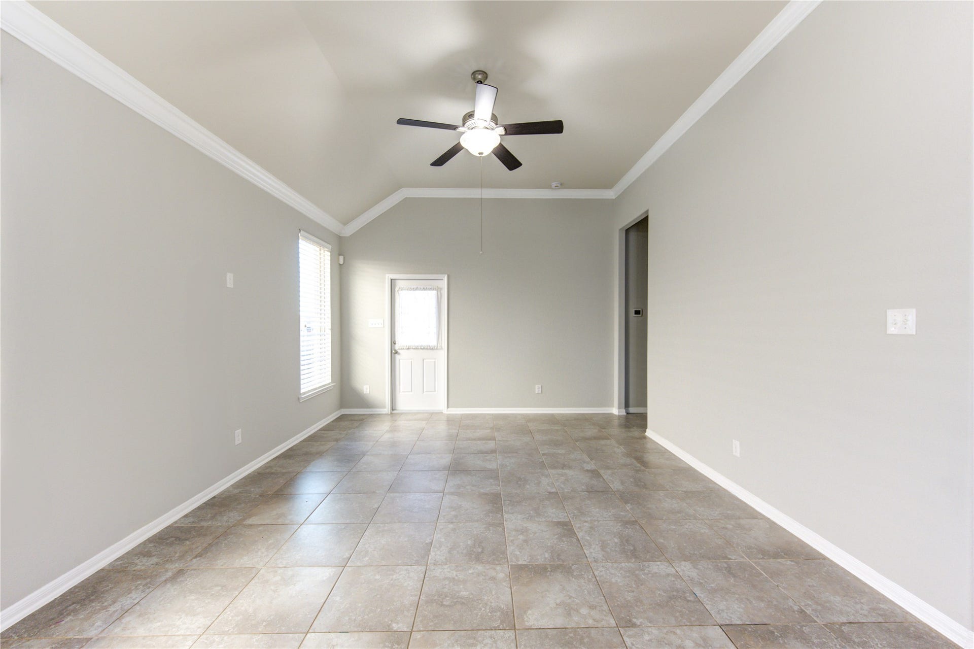 5314 Silver Ledge Drive, Katy, TX 77493 This photo showcases a spacious open-concept living area with a modern kitchen featuring dark cabinets, a large island, and stainless steel appliances. The room is bright with natural light from multiple windows, and the tile flooring offers a clean, contemporary feel. The ceiling fan and neutral color palette add to the inviting atmosphere.
