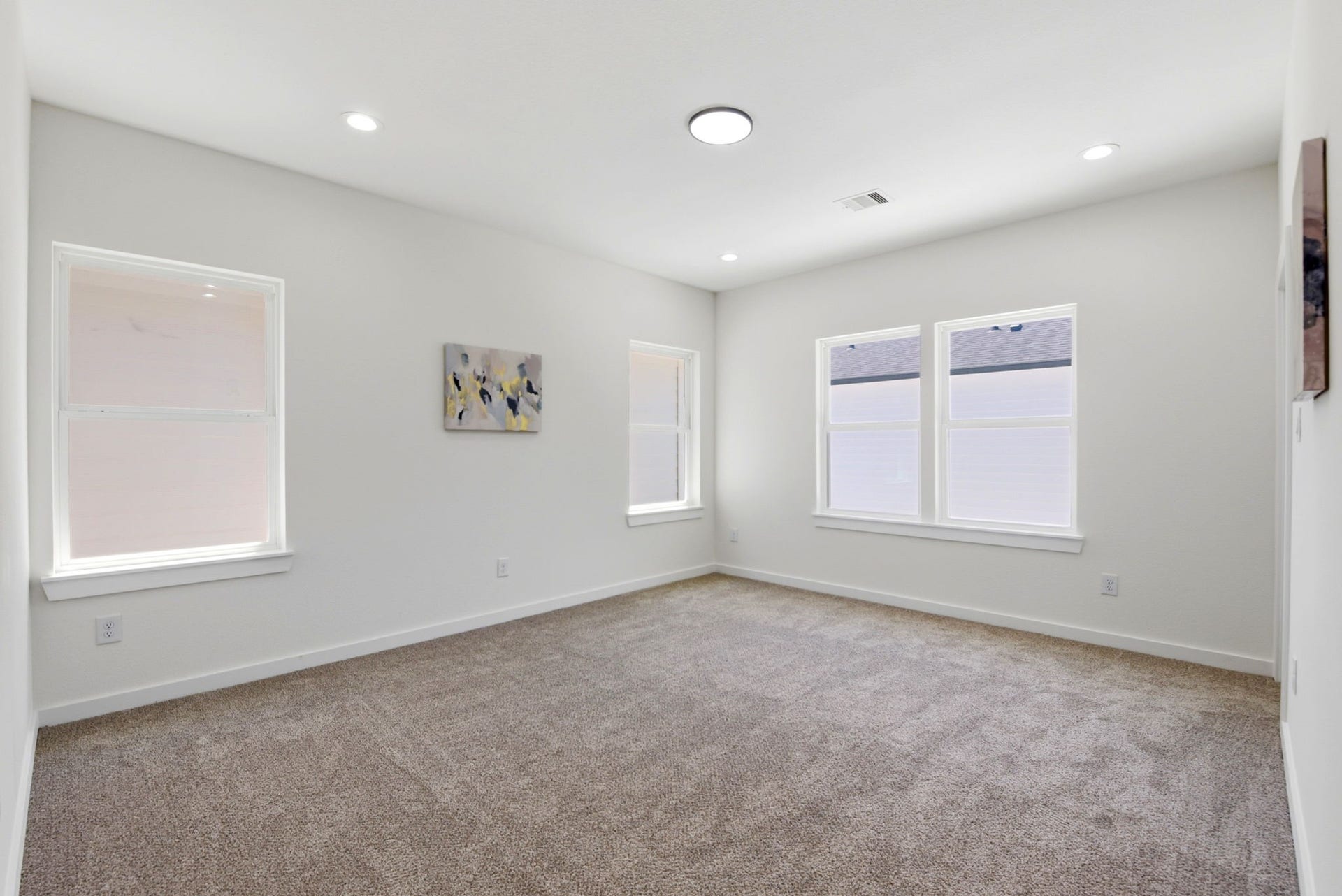 6117 Haight Street, Houston, TX 77028 Bright and spacious primary bedroom with neutral walls and cozy carpeting, featuring recessed lighting and large windows for ample natural light.