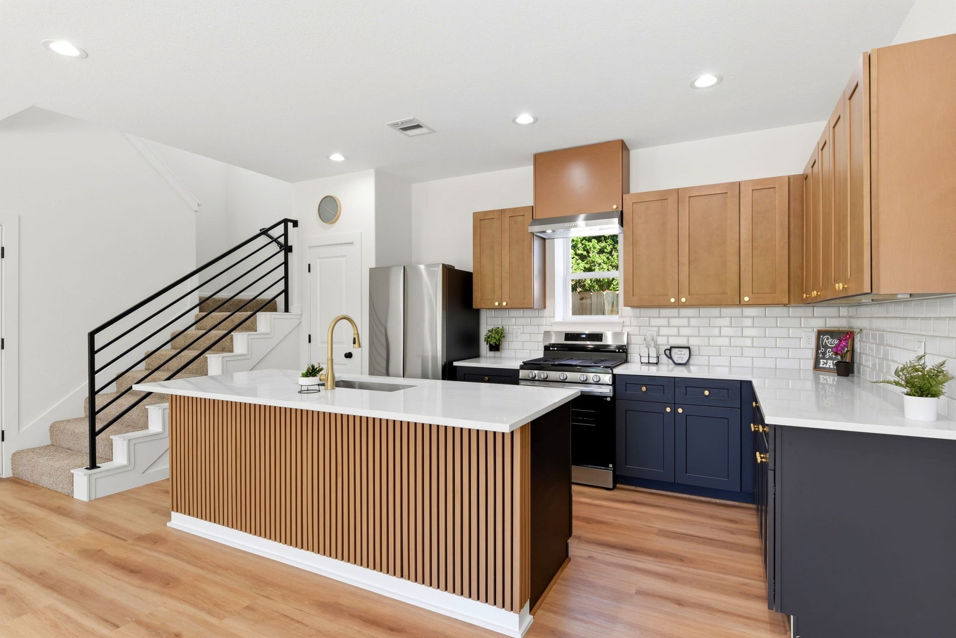 6117 Haight Street, Houston, TX 77028 This kitchen features a modern design with light wood cabinetry, a sleek island with vertical paneling, and stainless steel appliances.