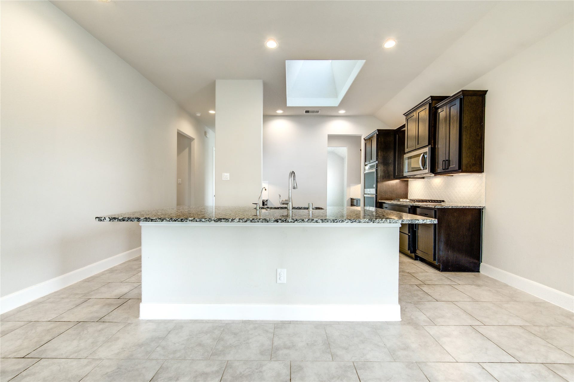 2334 Green Kale Drive, Richmond, TX 77406 Sleek dark cabinetry, granite counter tops, skylight, additional walk-in pantry, and a center island make the perfect place for meal prep and gatherings.