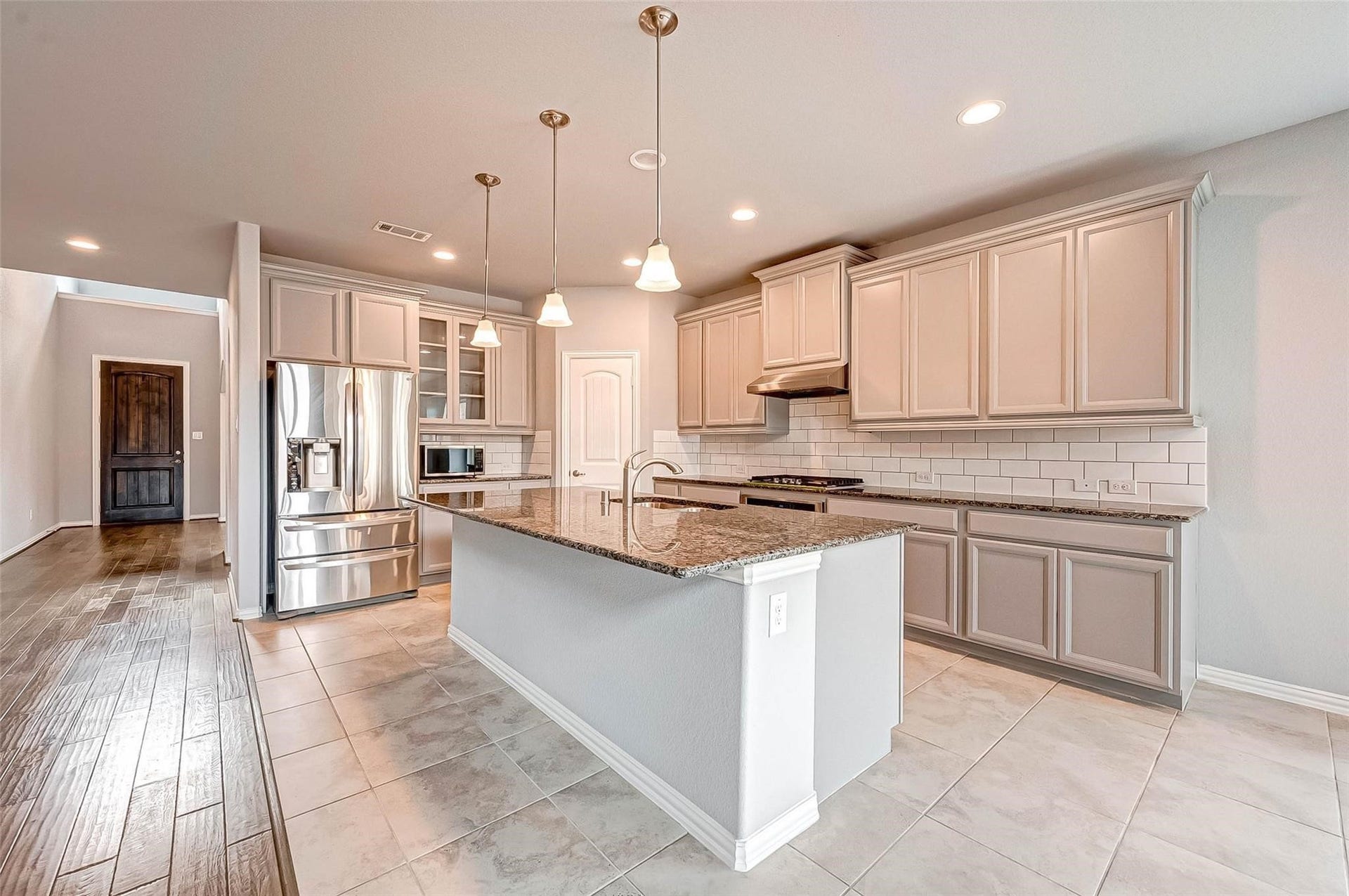 23514 San Ricci Court, Richmond, TX 77406 Spacious kitchen featuring a large granite island, ample cabinetry, stainless steel appliances, and pendant lighting.