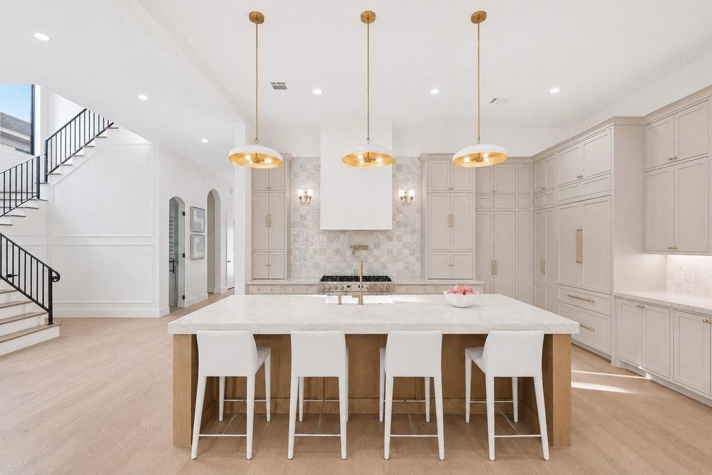 Oversized white oak island with plenty of seating, pendants, expansive run of countertop, under cabinet lighting and soft close doors