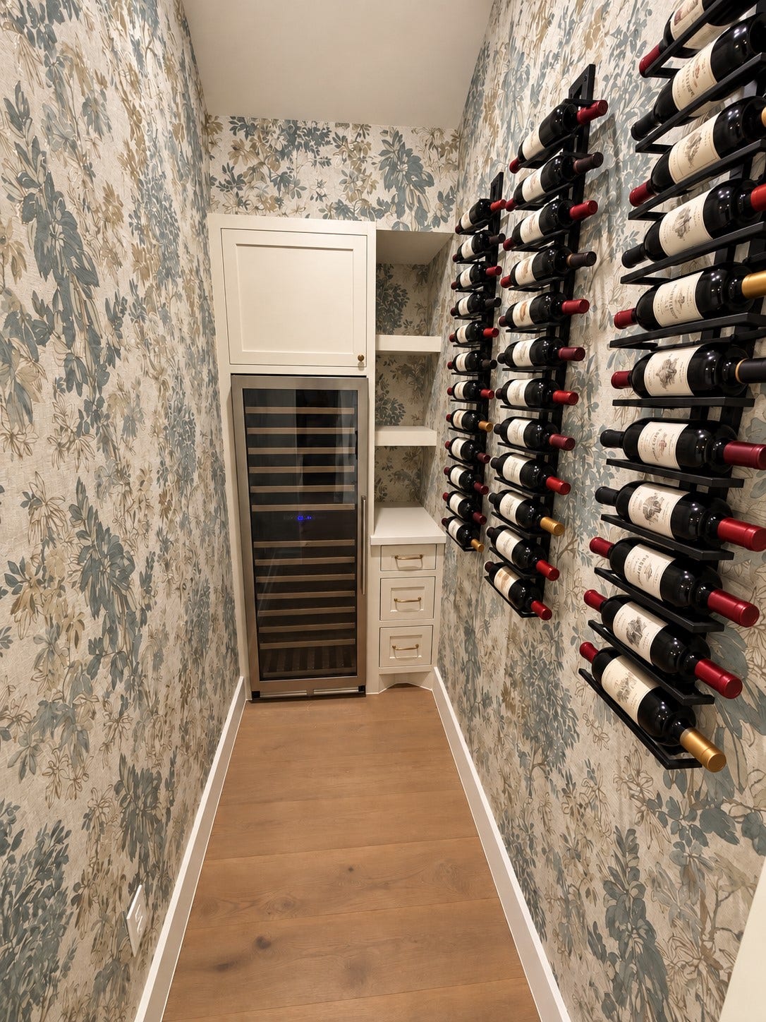 Dedicated wine room with oversized wine fridge and custom built ins and wallpaper