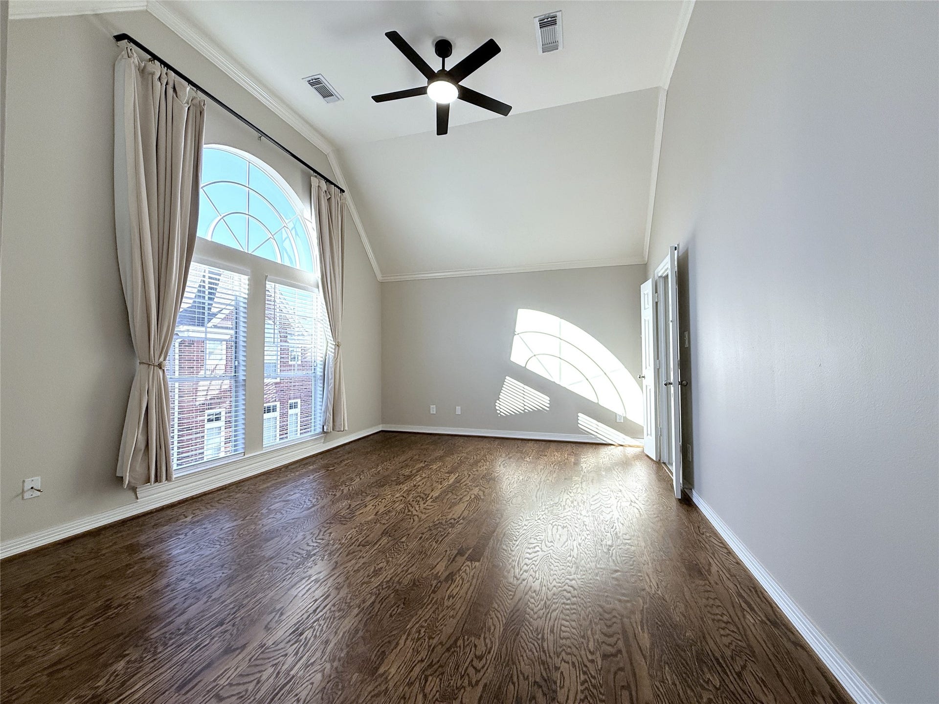 1963 Peden Street, Houston, TX 77019 Natural light flows into the primary bedroom from arched windows. To darken the room, the landlord has provided drapery.