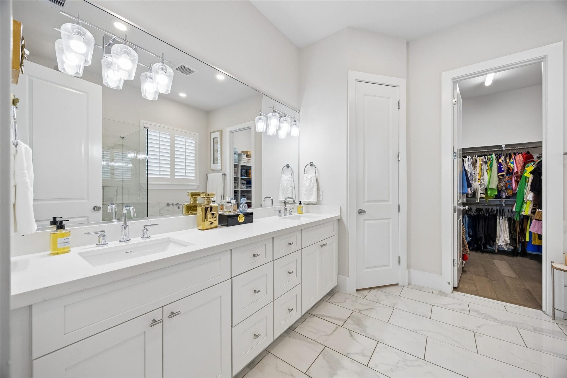 1226 W 21st Street, Houston, TX 77008 The spa-like primary ensuite feels crisp and luxurious with a long dual-sink vanity, bright designer lighting, beautiful tile flooring, and a large walk-in closet that keeps everything close and organized.