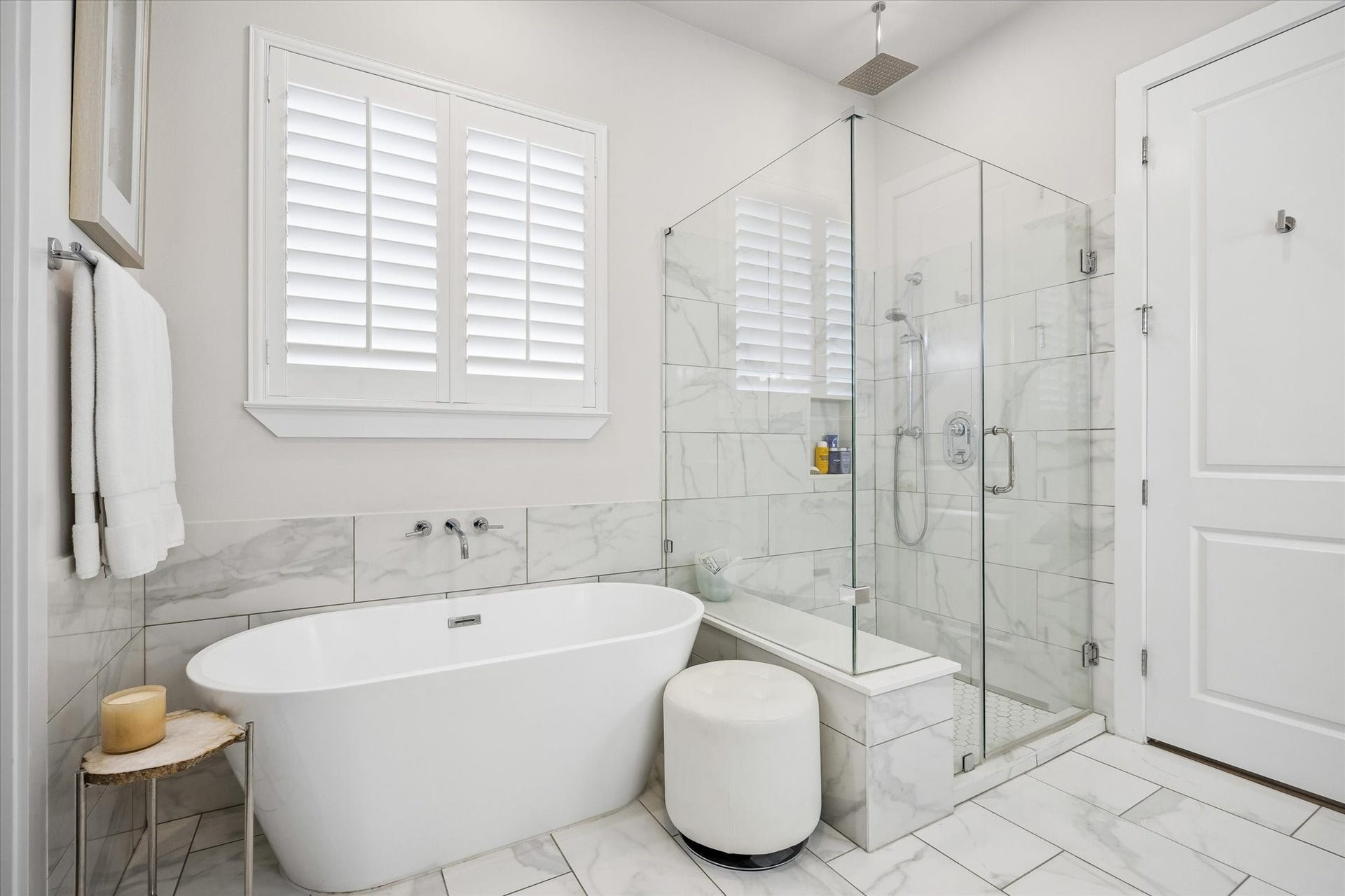 1226 W 21st Street, Houston, TX 77008 Enjoy a daily dose of luxury in this marble-wrapped primary bathroom with a freestanding soaking tub, oversized glass shower, wood shuttered window, and fresh modern finishes that feel calm and elevated.