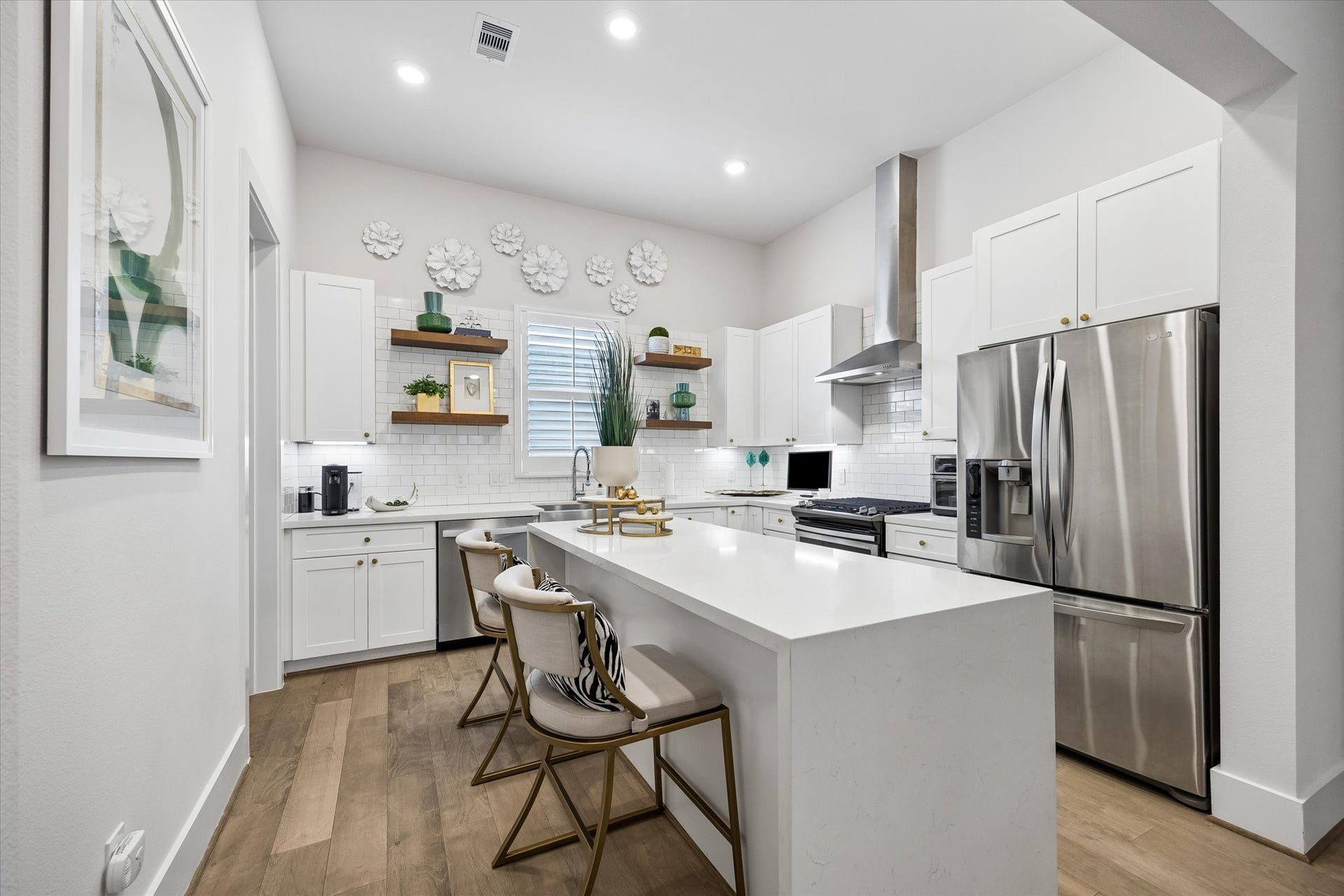 1226 W 21st Street, Houston, TX 77008 This stylish island kitchen brings the wow factor with quartz countertops, a waterfall island with bar seating, stainless-steel appliances, a sleek hood vent, open shelving, and crisp modern cabinetry.