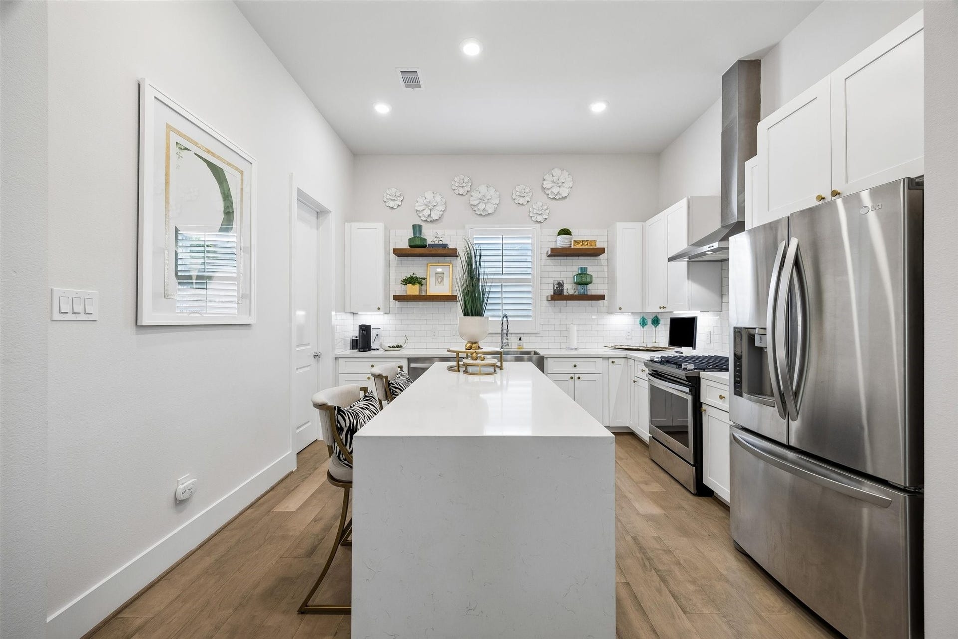 1226 W 21st Street, Houston, TX 77008 Crisp, clean, and ready to serve, this beautiful kitchen is filled with high-end style and everyday function, including a waterfall quartz island and countertops, subway tile backsplash, under-cabinet lights, stainless-steel appliances, a sleek hood vent, open shelving, modern cabinetry and a large walk-in pantry.