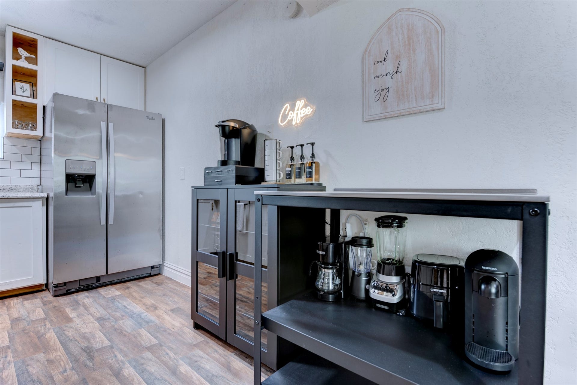 1121 Panama Street, #B, Houston, TX 77009 Kitchen and coffee bar wide view showing Whirlpool stainless side-by-side refrigerator with ice and water dispenser, white shaker upper cabinets with natural pine open cubbies, white subway tile backsplash, granite countertops, and dedicated black metal coffee and appliance station with Keurig and Nespresso machines.
