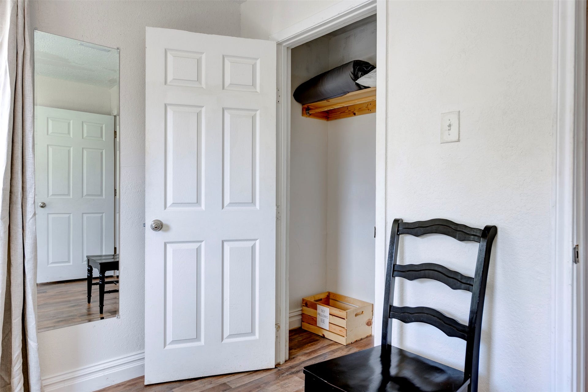 1121 Panama Street, #B, Houston, TX 77009 Bedroom closet detail showing white six-panel door, natural wood upper shelf with hanging rod, and hardwood-style flooring throughout.