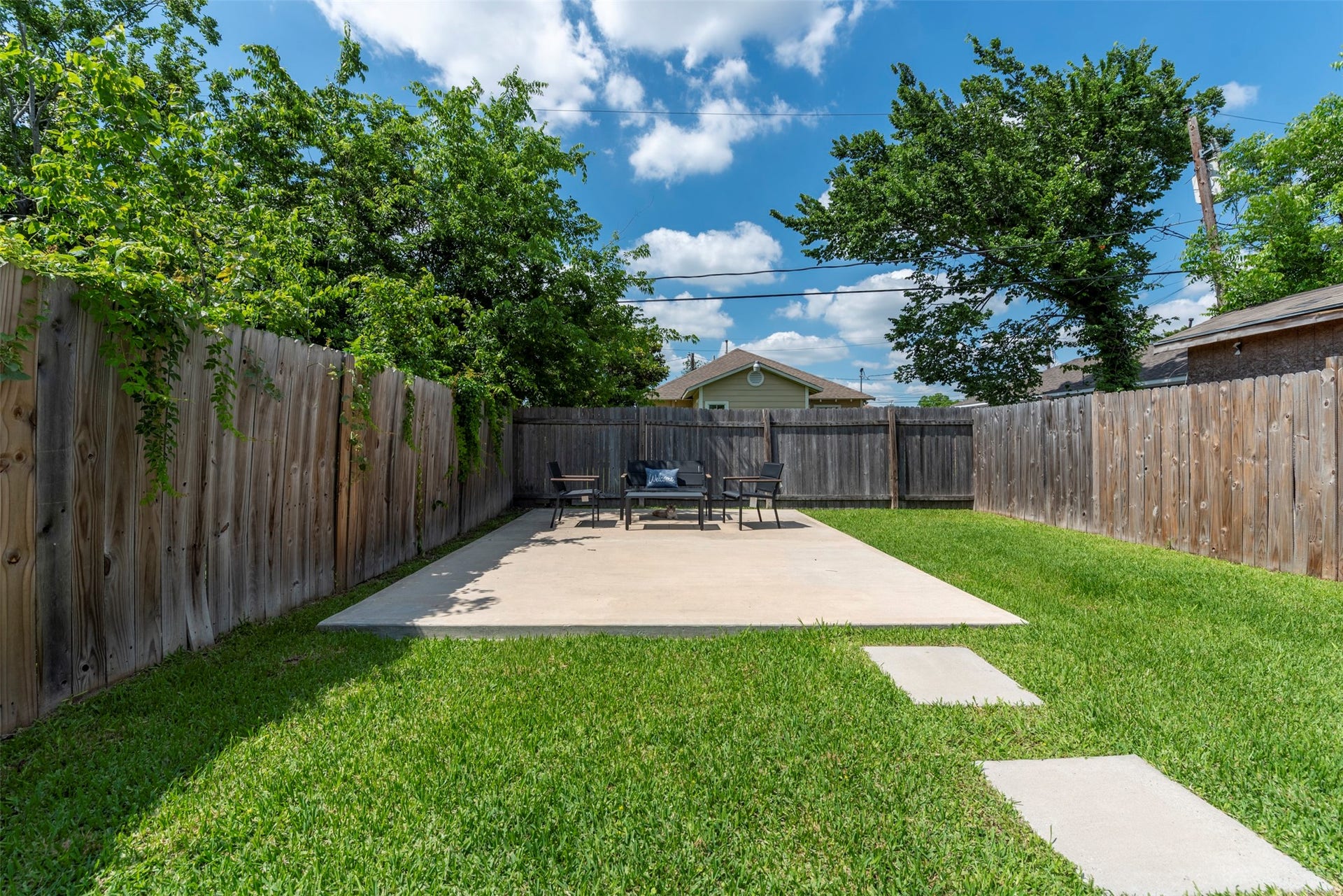 1121 Panama Street, #B, Houston, TX 77009 Spacious fully fenced backyard with a large poured concrete patio, mature shade trees, manicured lawn, and privacy wood fence on all three sides.