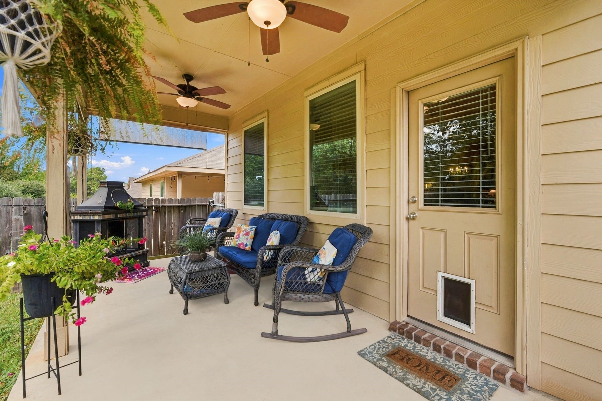11371 Dawn Beach Lane, Conroe, TX 77304 Charming covered patio with cozy seating, ceiling fans, and lush greenery, perfect for relaxing and entertaining outdoors.