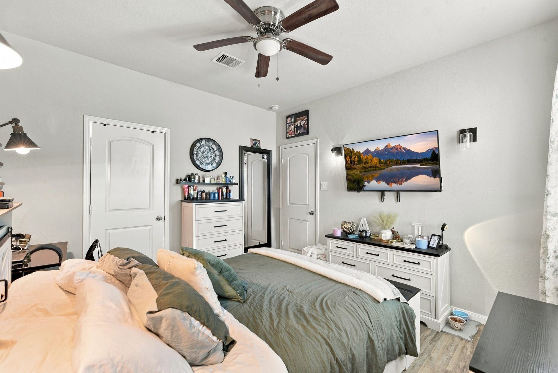11371 Dawn Beach Lane, Conroe, TX 77304 Spacious bedroom featuring a cozy bed, modern ceiling fan, and ample storage with a dresser and shelves. A wall-mounted TV adds a contemporary touch, while soft lighting creates a relaxing atmosphere.