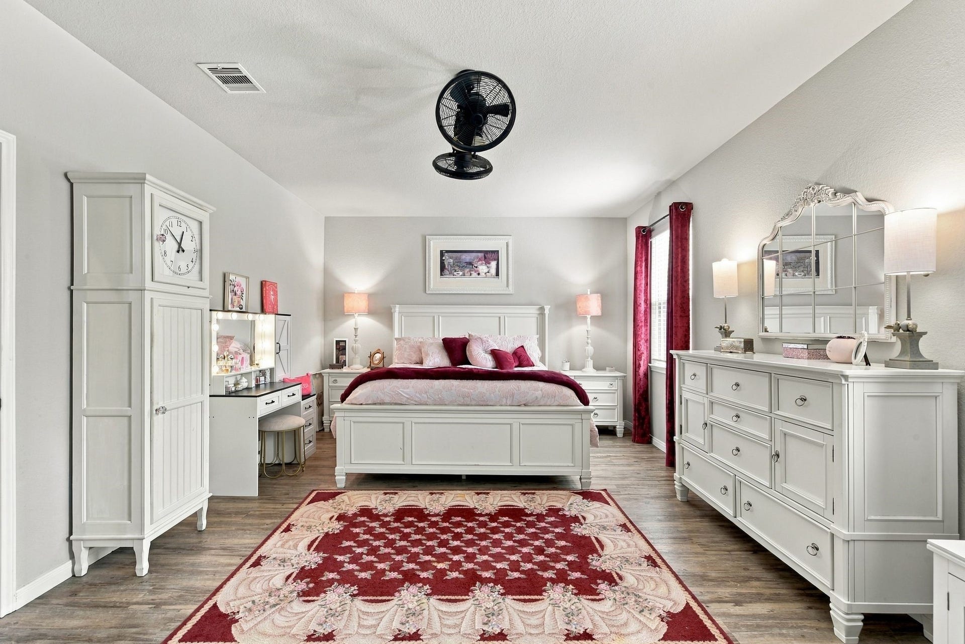 11371 Dawn Beach Lane, Conroe, TX 77304 Elegant bedroom featuring a cozy bed with plush red accents, complemented by white furniture and hardwood flooring.