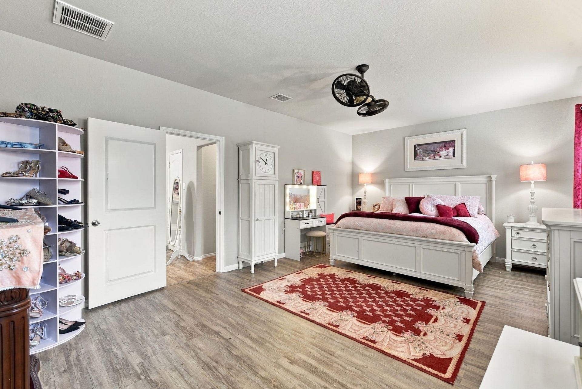11371 Dawn Beach Lane, Conroe, TX 77304 Spacious bedroom featuring elegant white furniture, a cozy bed adorned with plush red and pink accents, and ample storage with a charming shoe rack.