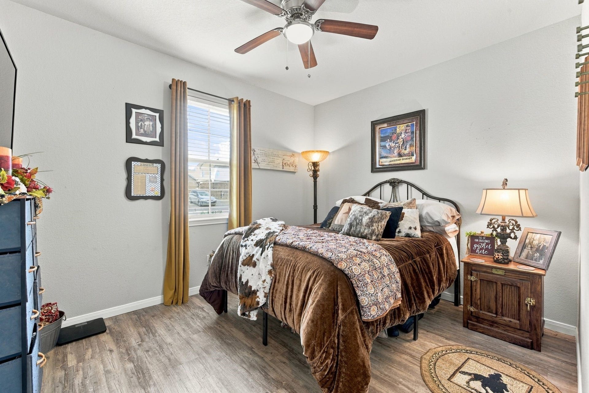 11371 Dawn Beach Lane, Conroe, TX 77304 Cozy bedroom featuring warm wood flooring, a ceiling fan, and rustic decor, complemented by ample natural light from a large window.