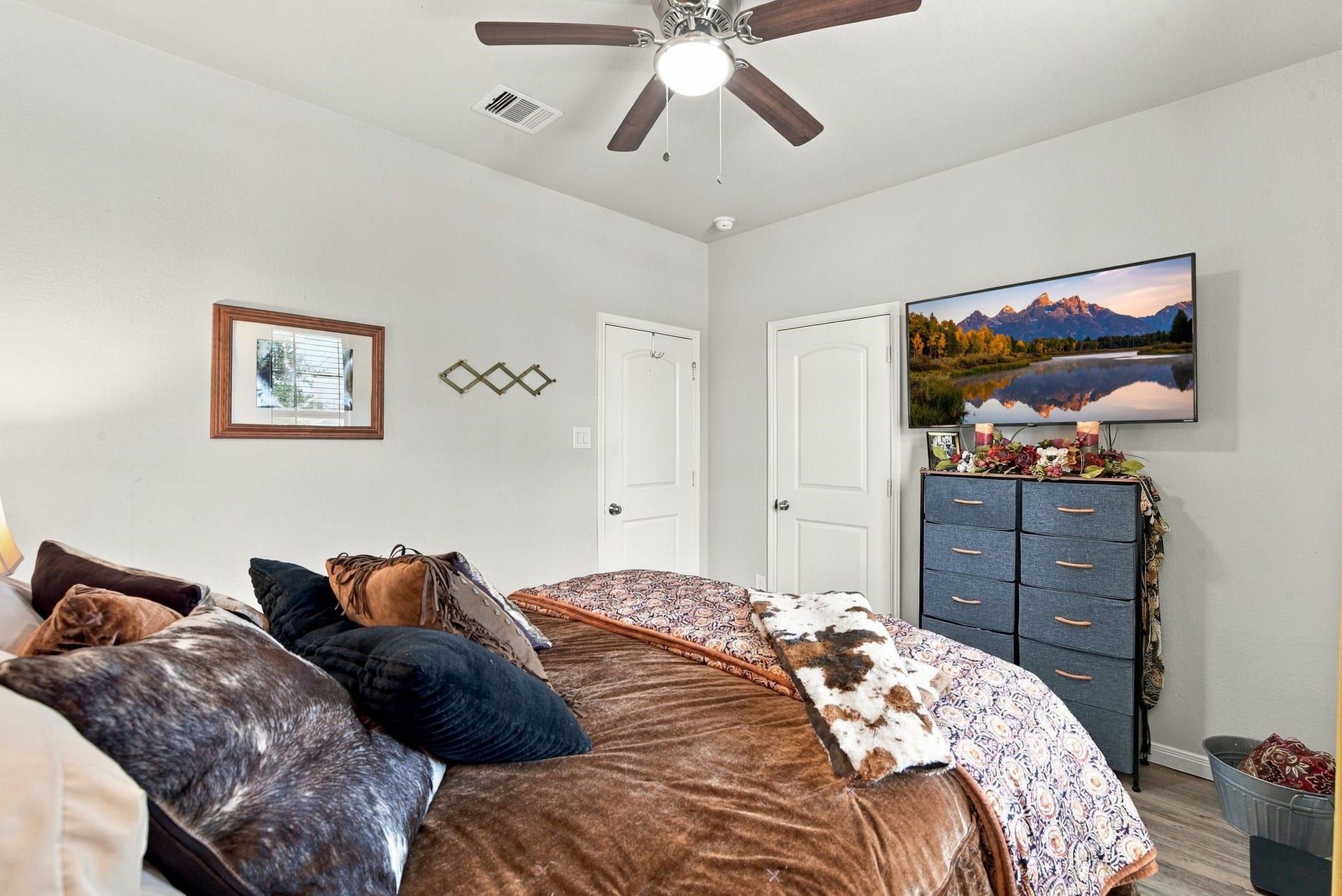 11371 Dawn Beach Lane, Conroe, TX 77304 Cozy bedroom with neutral tones, featuring a ceiling fan, a TV mounted above a stylish dresser, and plush bedding for a comfortable retreat.